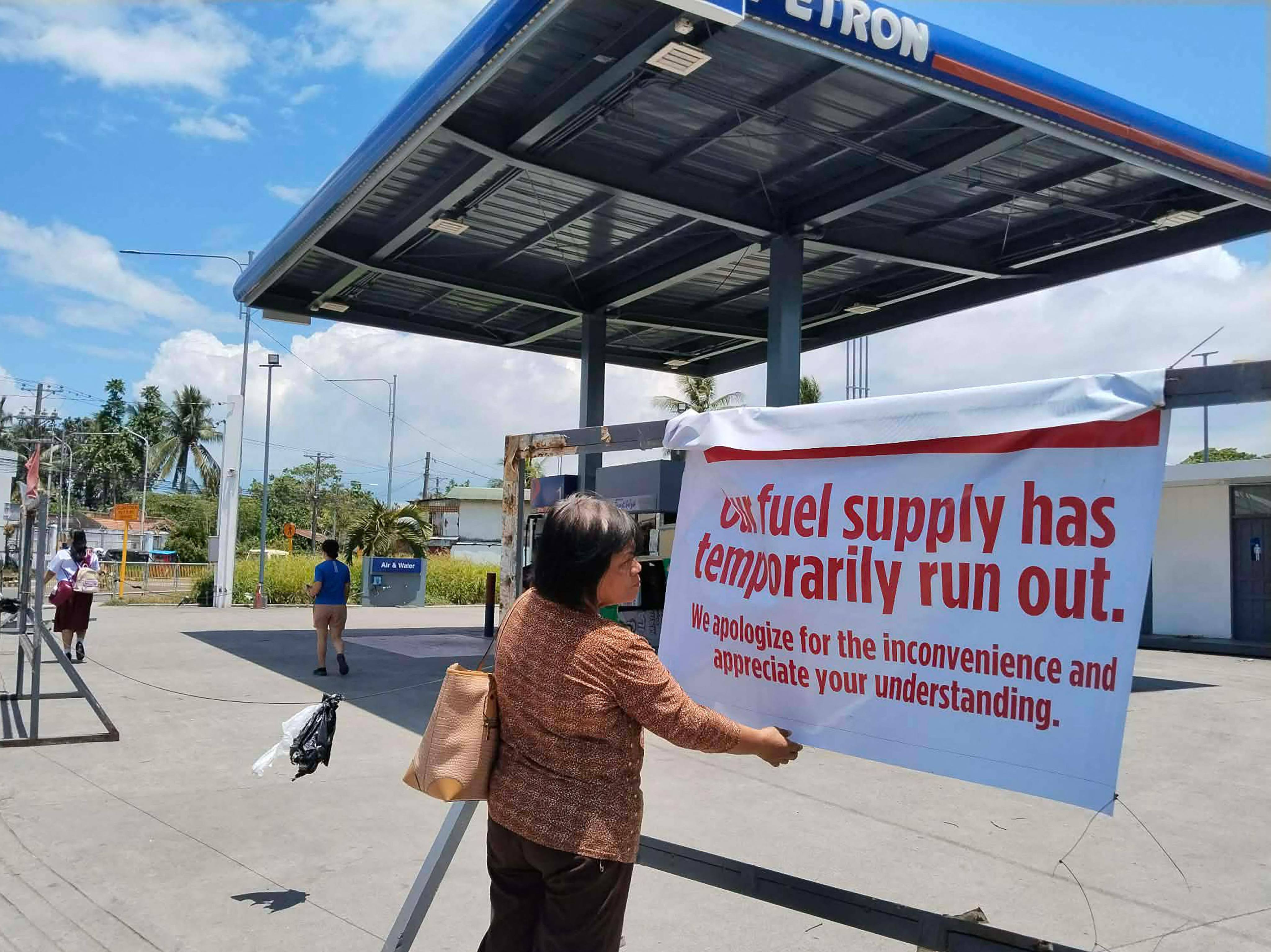 A pedestrian reads a sign at a petrol station in Tacloban City, Leyte province, central Philippines on Monday. Photo: AFP