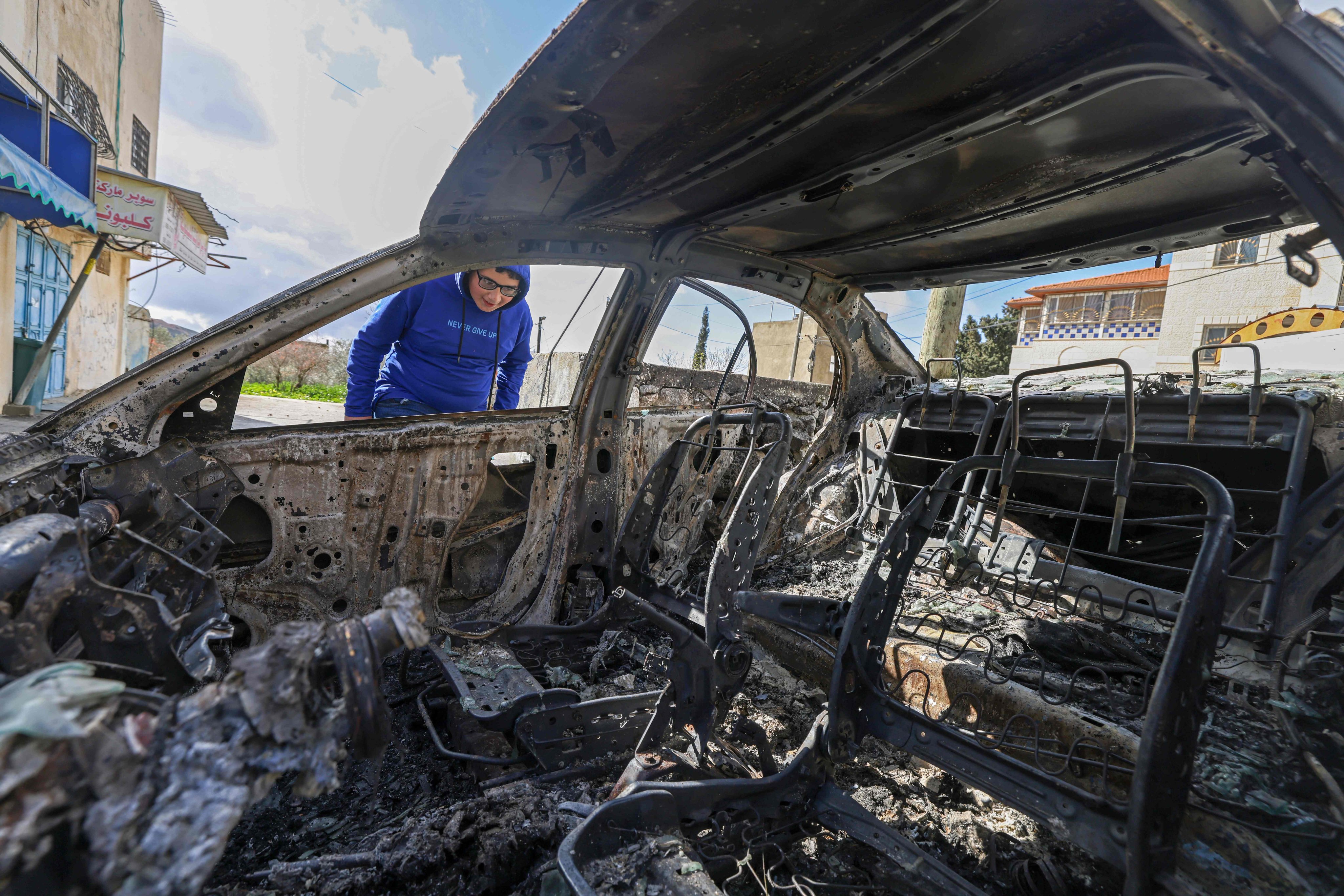 A Palestinian boy looks at a burnt vehicle following a reported attack by Israeli settlers in Jalud village, south of Nablus in the occupied West Bank. Photo: AFP