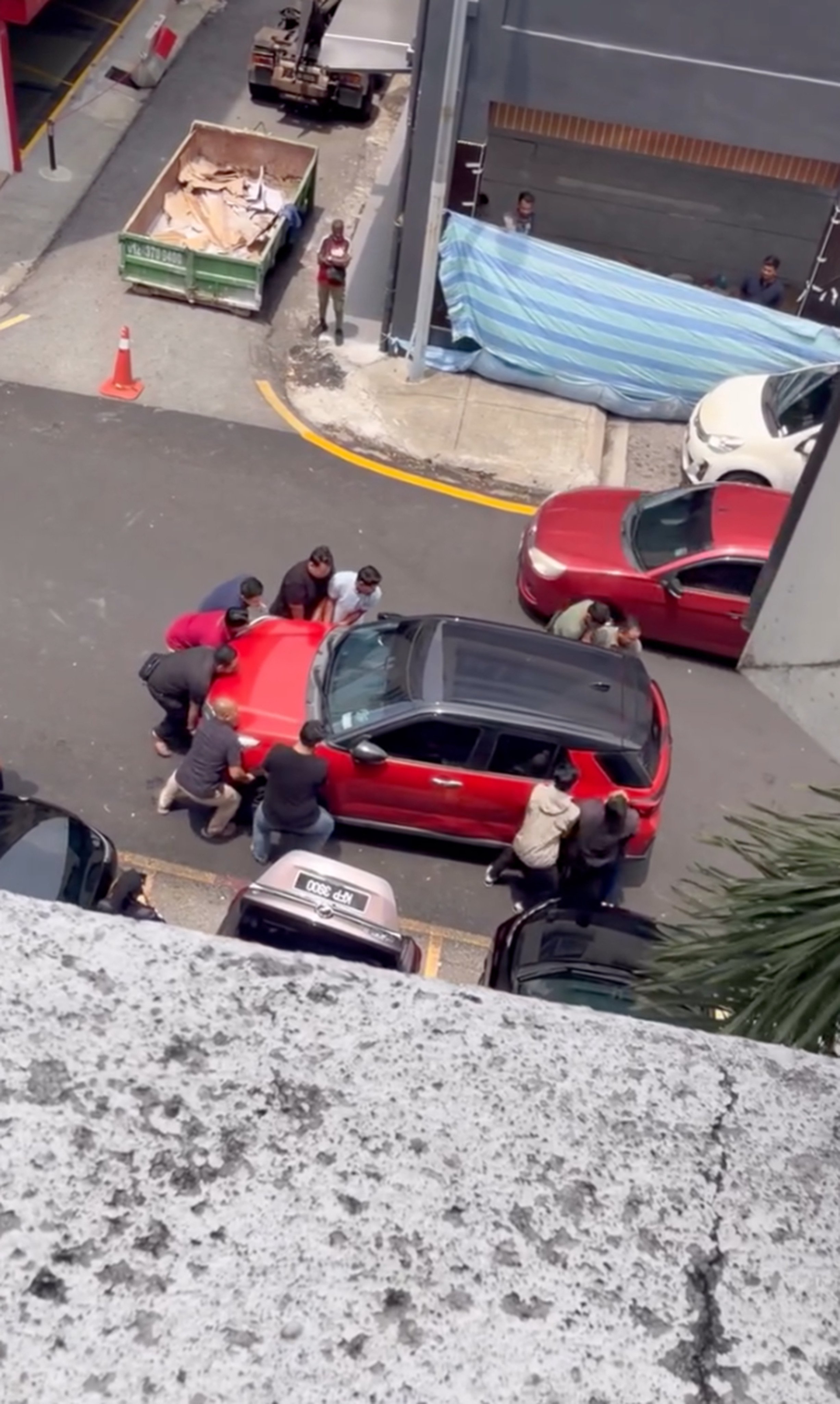 Men lift a car that is blocking a driver from reversing out. Photo: Threads/wnasyh