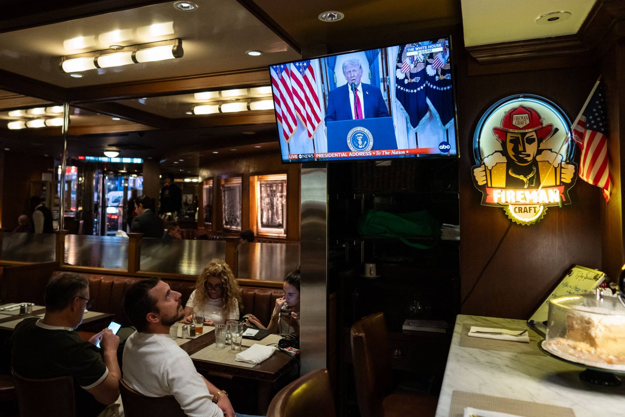 People in New York watch as US President Donald Trump makes a national address on television. Photo: AFP