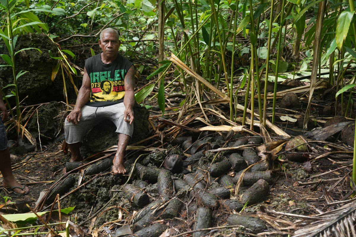 Billy, a resident of the village of Yandina in Russell Islands, Solomon Islands, sits next to unexploded munitions near his home. Photo: UNDP Pacific Office/Christopher Teasdale