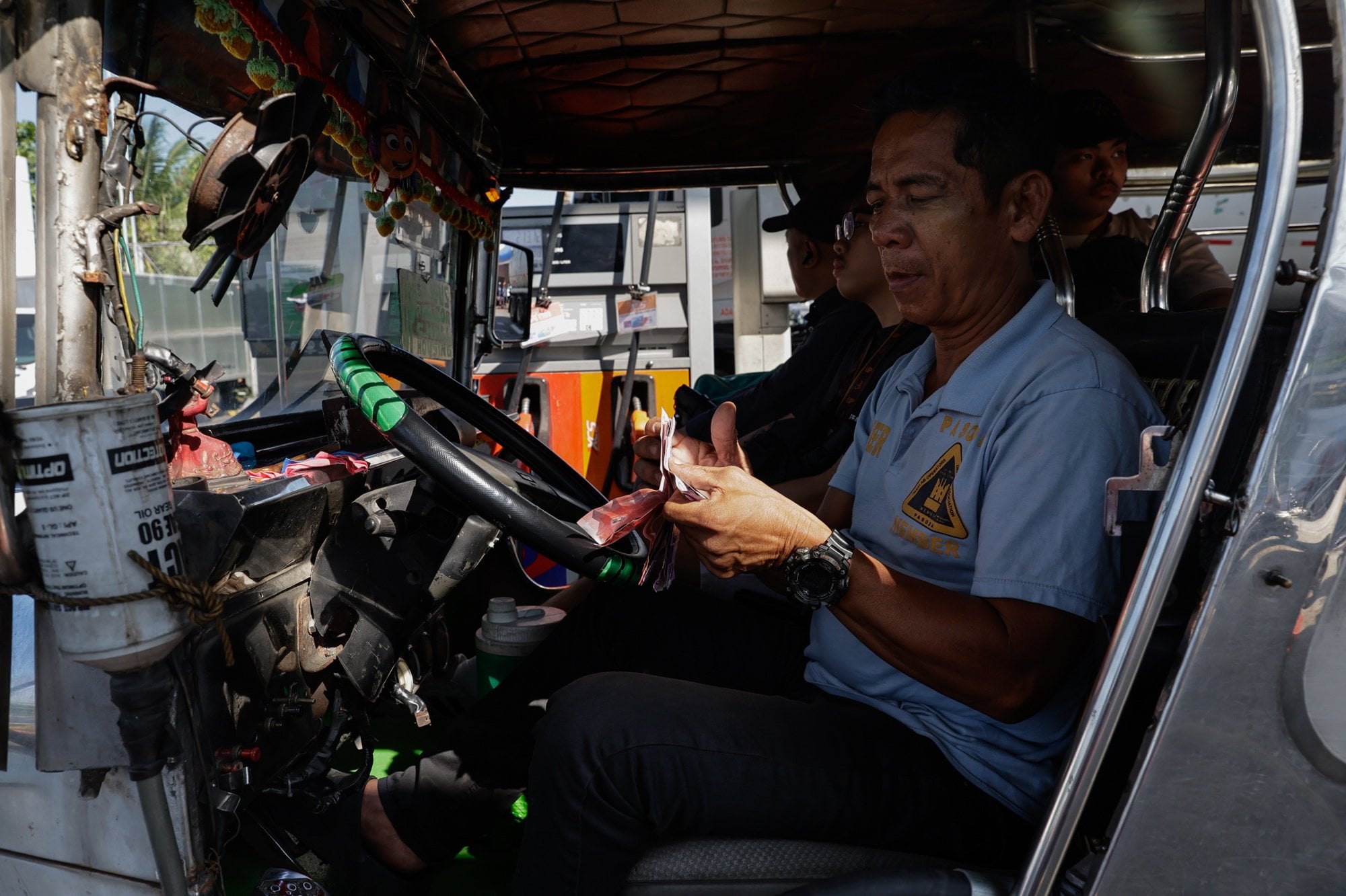 A jeepney, or local minibus, driver counts cash to pay at a fuel station in Quezon City, Metro Manila, Philippines, on March 25. Fuel shortages and increases in the cost of living  can push vulnerable communities towards human traffickers. Photo: EPA