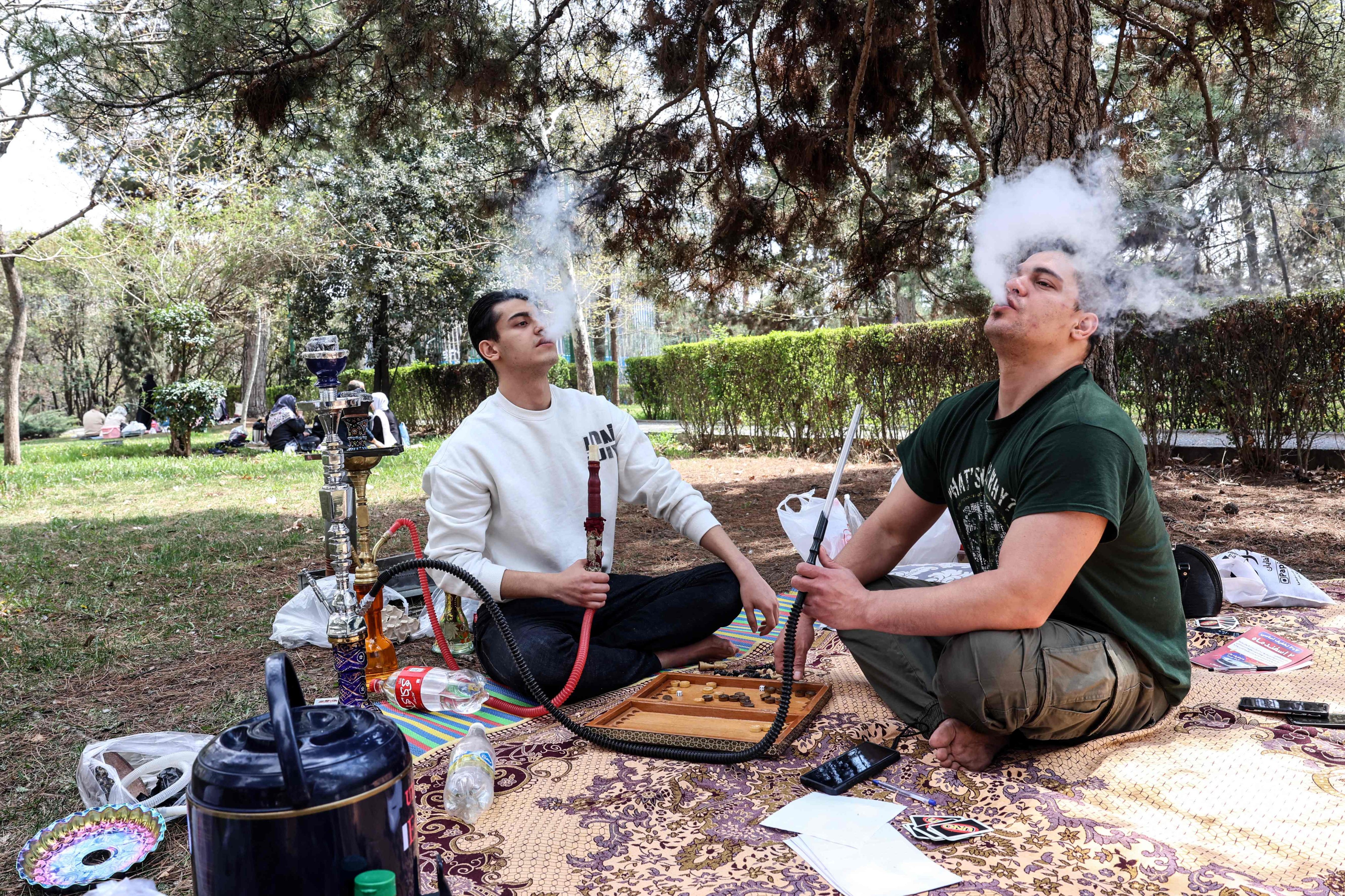 Iranian men smoke waterpipes as they sit in Tehran’s Mellat Park on Thursday. Photo: AFP