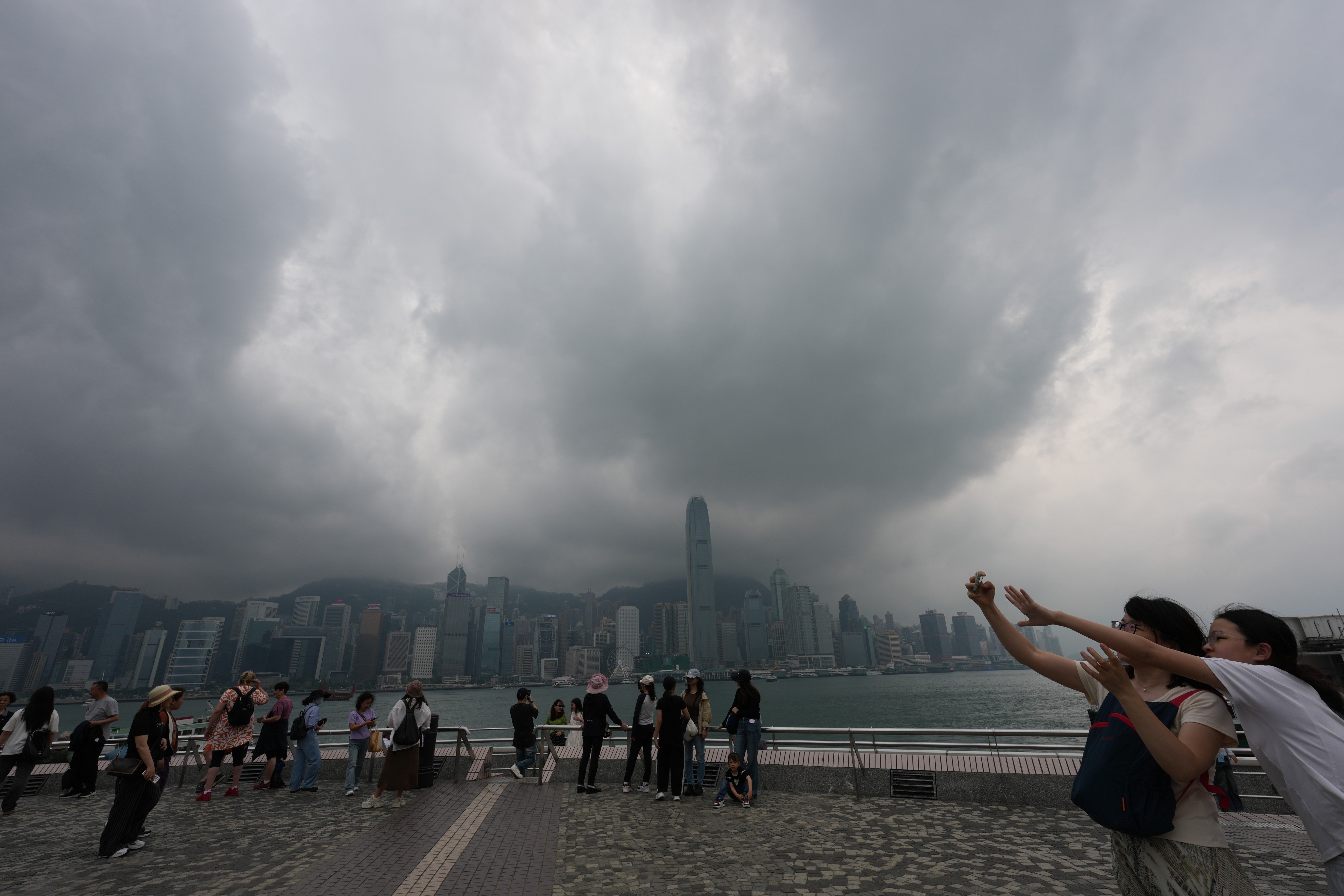 Tourists take pictures at the Tsim Sha Tsui waterfront amid cloudy weather on Friday. Photo: Jelly Tse