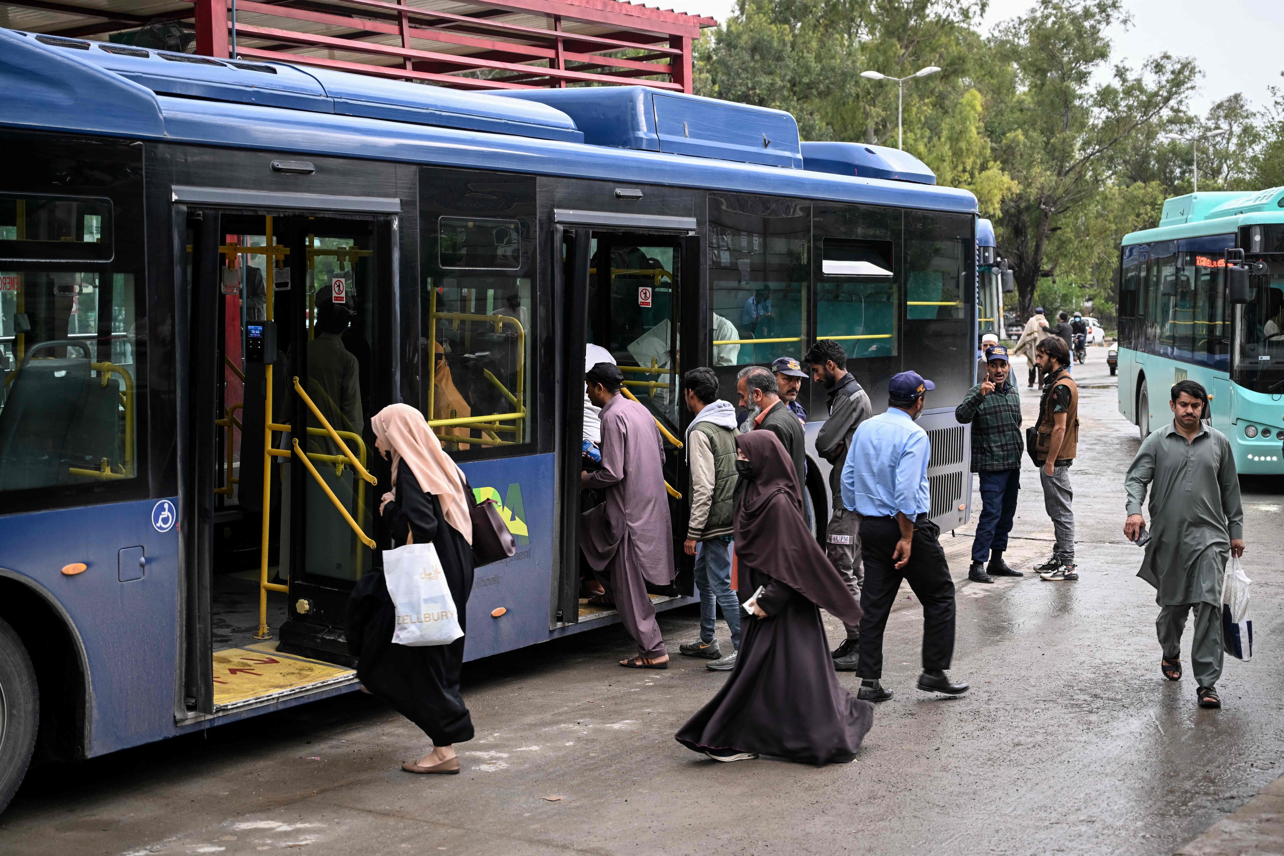 Passengers board a government bus in Islamabad on Friday. Photo: AFP
