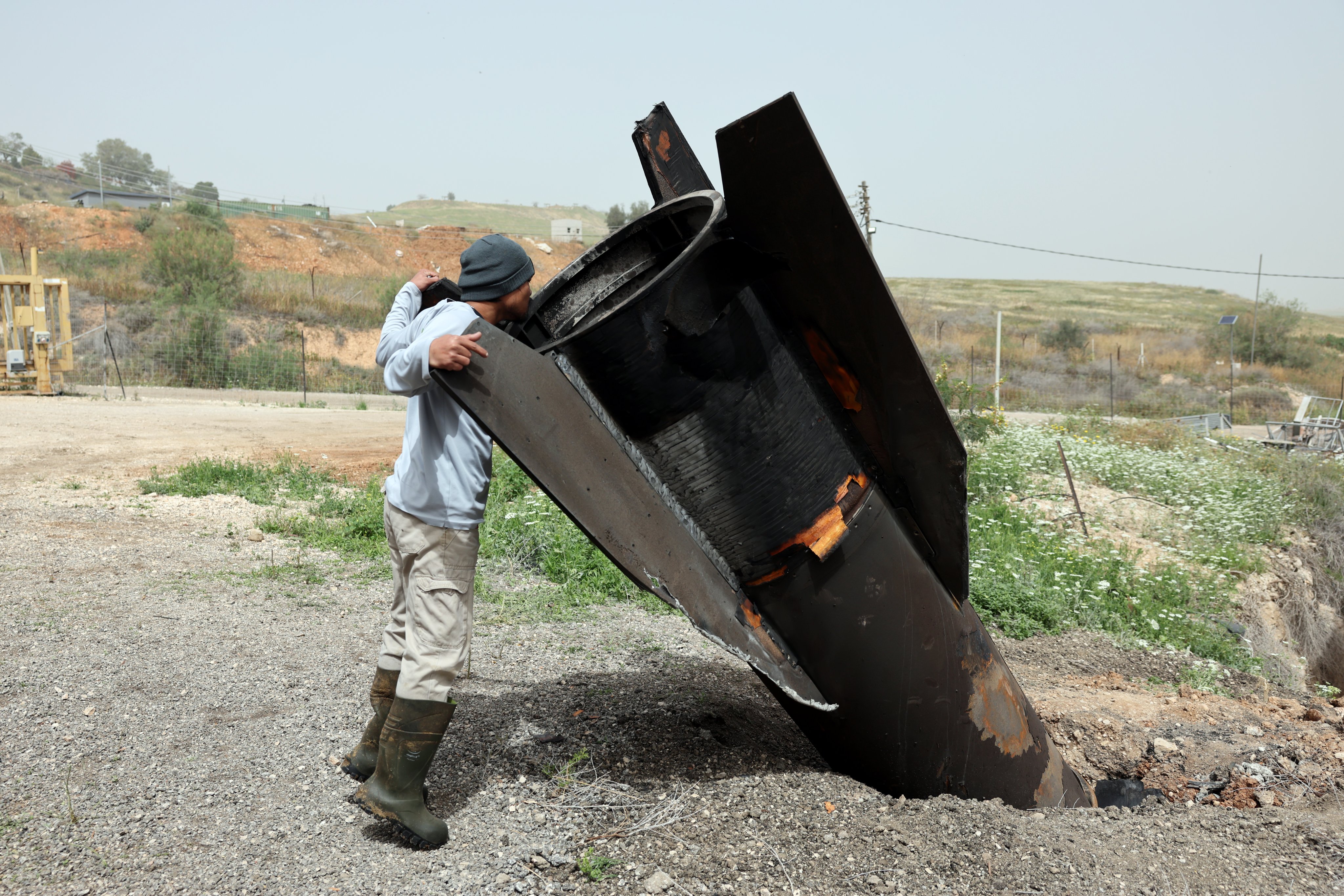 A Thai agricultural worker examines the tail of an Iranian ballistic missile that hit near a cow barn in the Israeli settlement of Shadmot Mehola, in the West Bank. Photo: EPA