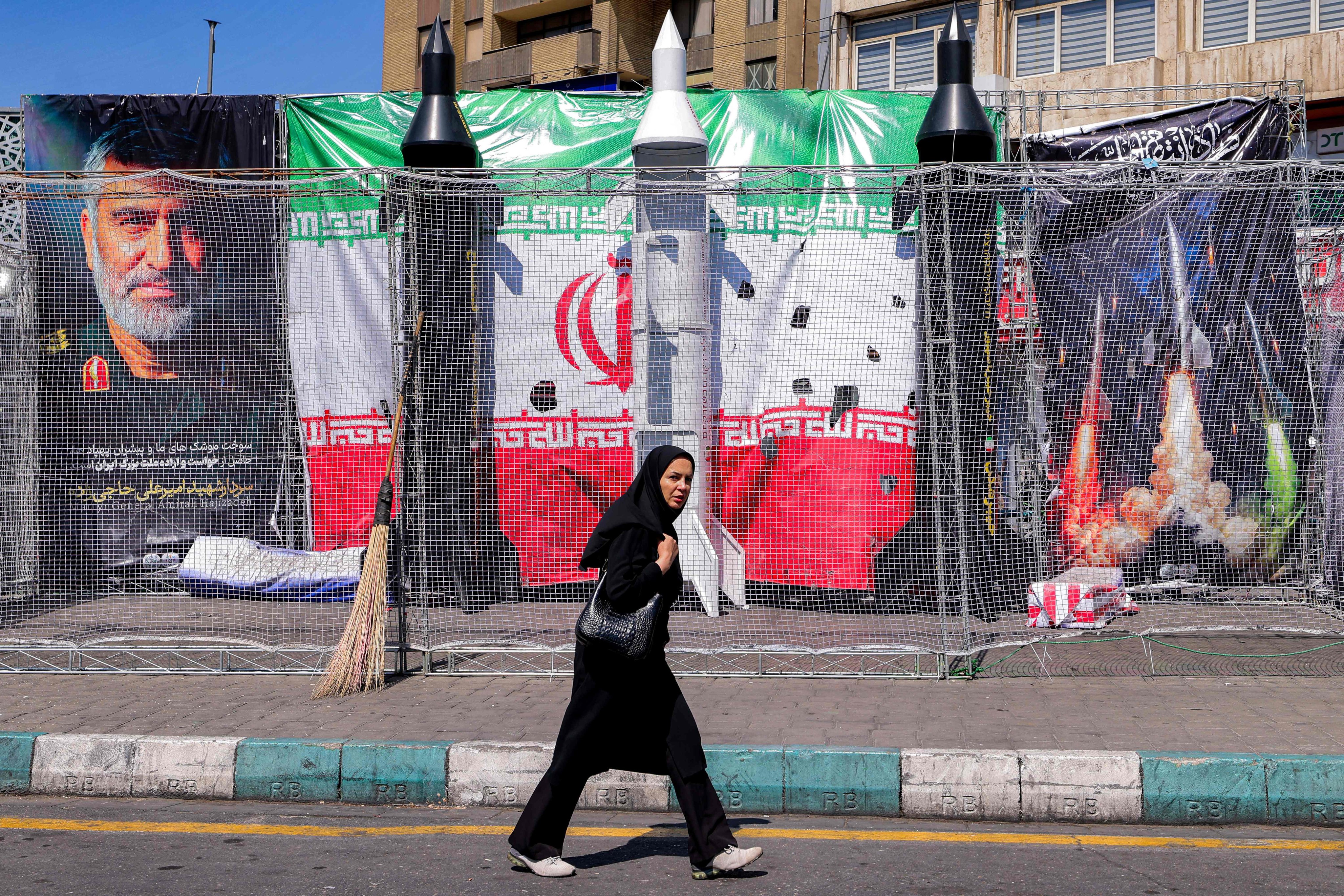 A woman walks past mockups of Iranian missiles in Tehran. Photo: AFP