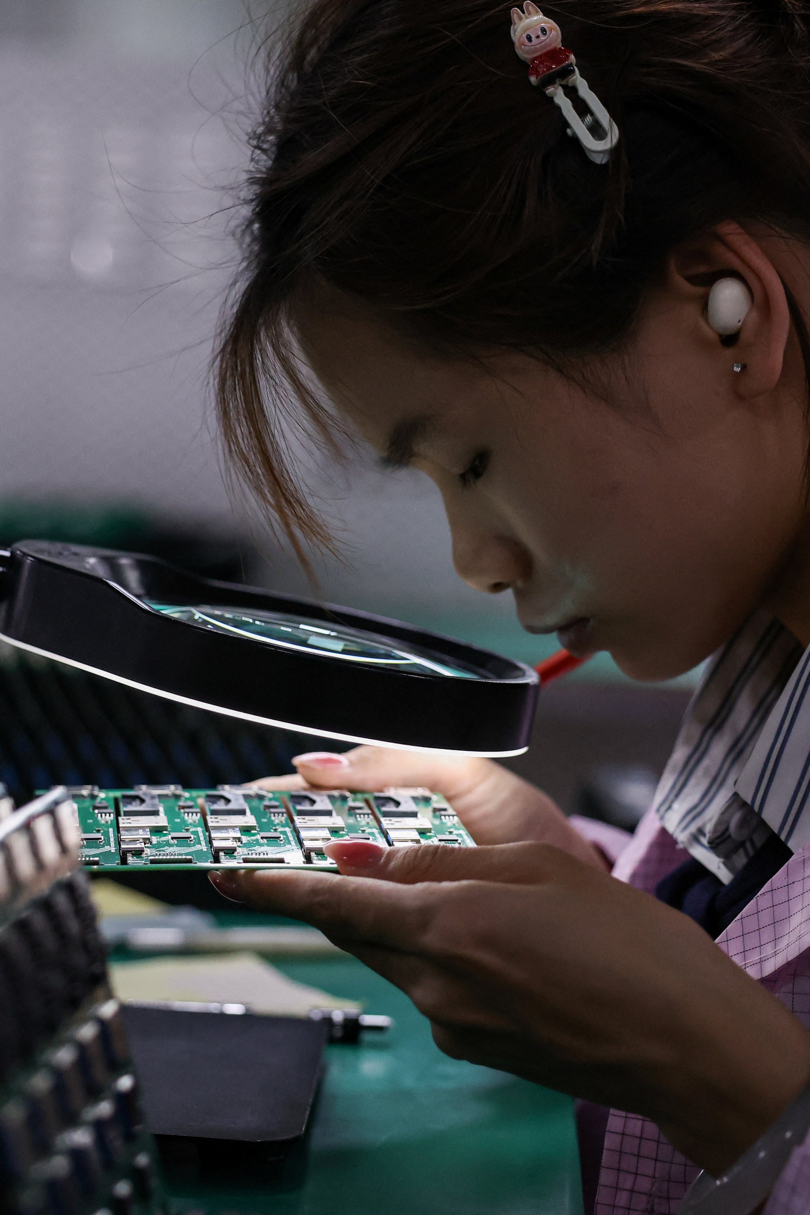 An employee inspects a printed circuit board at a factory which is in partnership with Agilian Technology, in Dongguan, Guangdong province, China March 16, 2026. REUTERS/Tingshu Wang