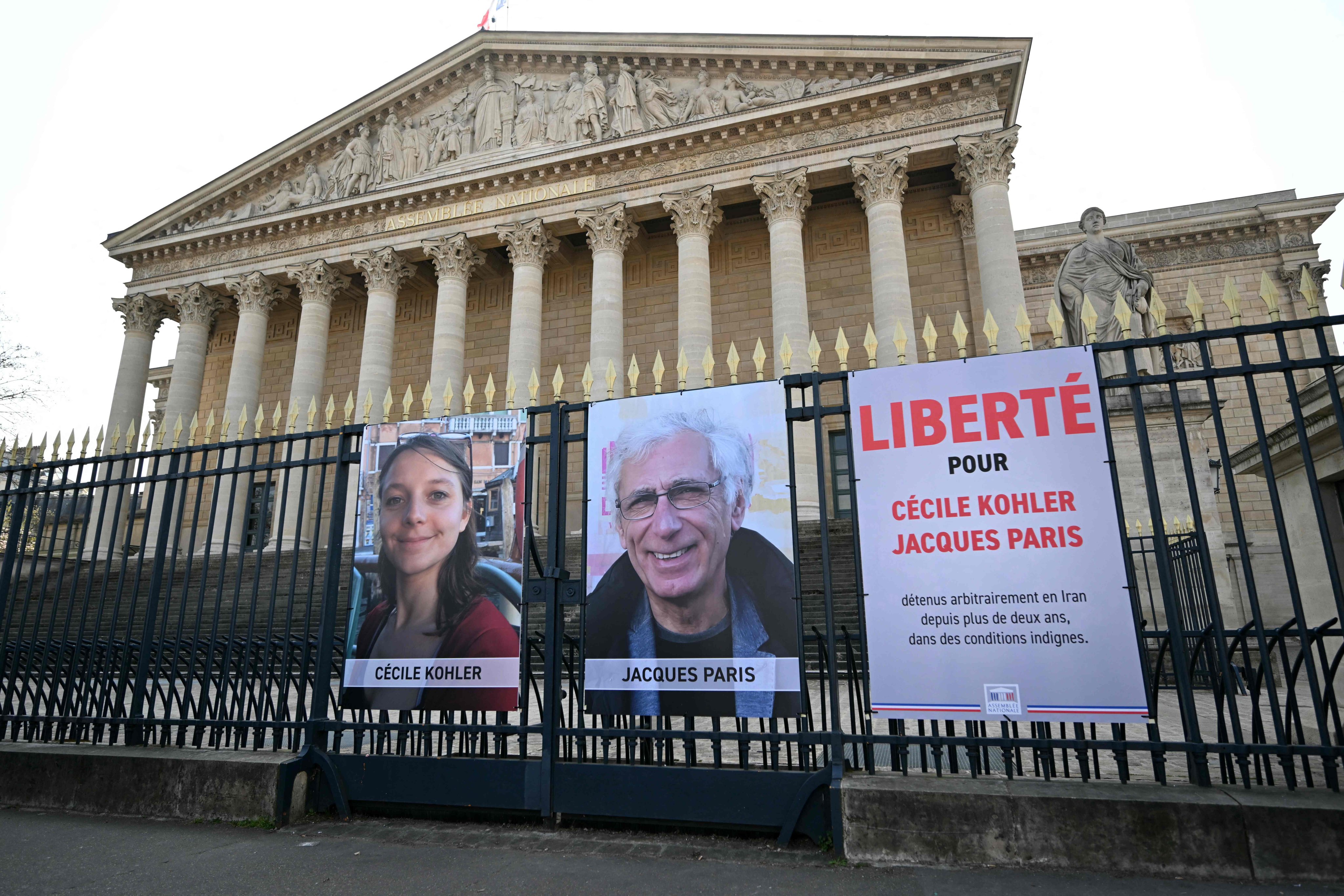 Portraits of Cecile Kohler (left) and her partner Jacques Paris along with a placard reading “Freedom for Cecile Kohler and Jacques Paris arbitrarily detained in Iran for over two years in appalling conditions” outside the Palais Bourbon, France’s National Assembly in 2025. Photo: AFP