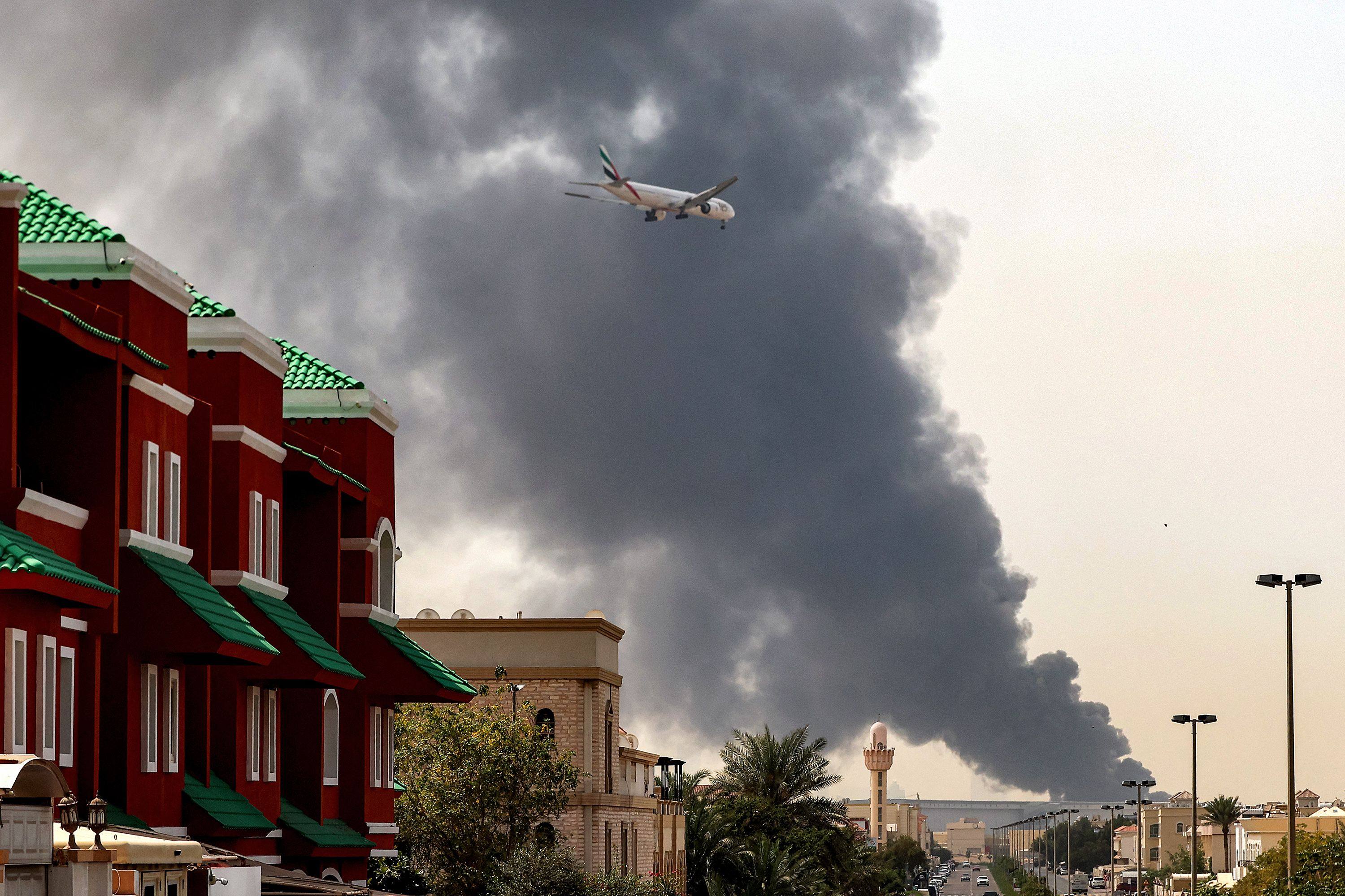 An Emirates aircraft prepares for landing as a smoke plume rises from a fire near Dubai International Airport on March 16. Photo: AFP