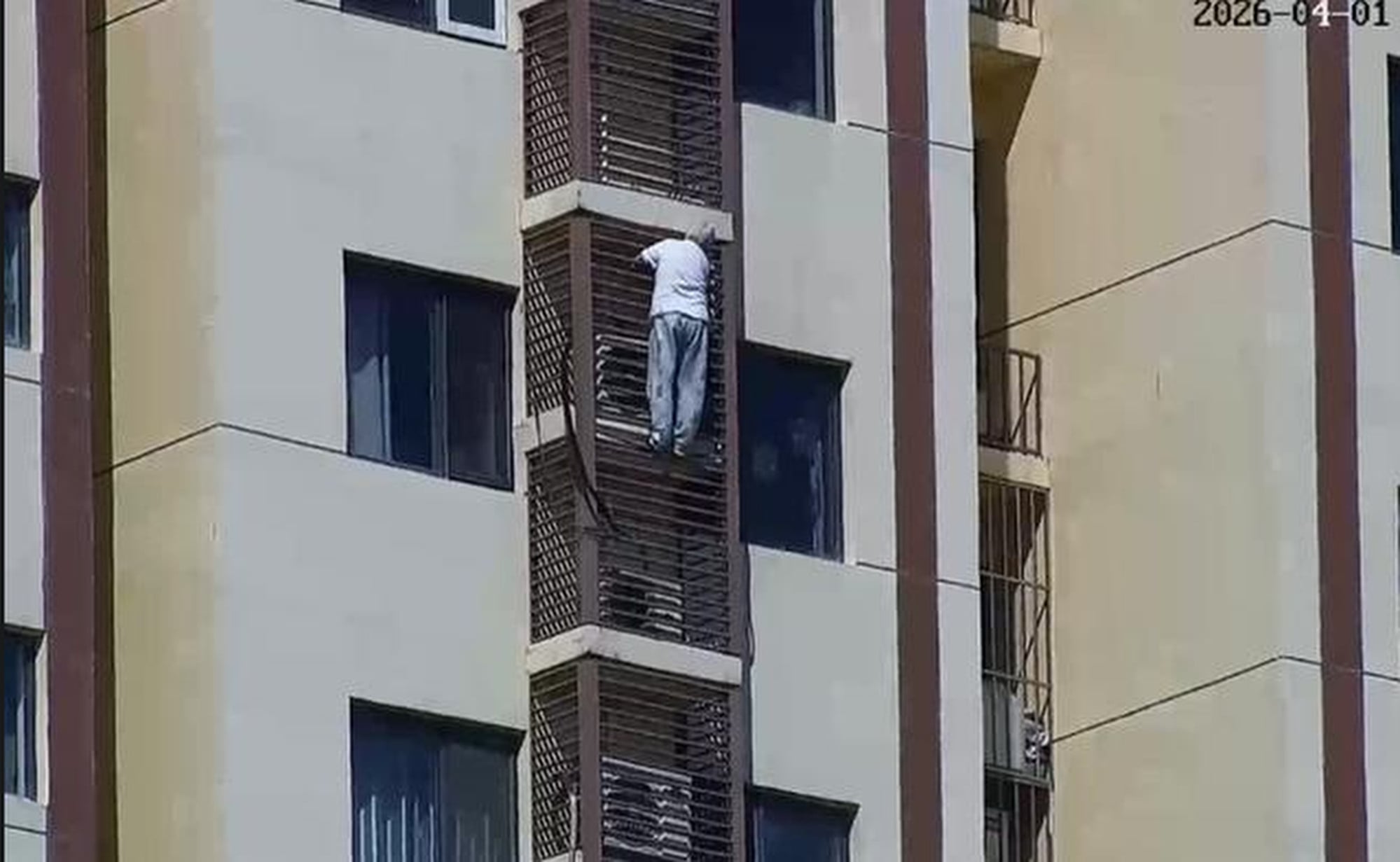 The 89-year-old, above, can be seen gripping on to the bars of an air-conditioning unit cage as she makes her way down the building. Photo: Sina