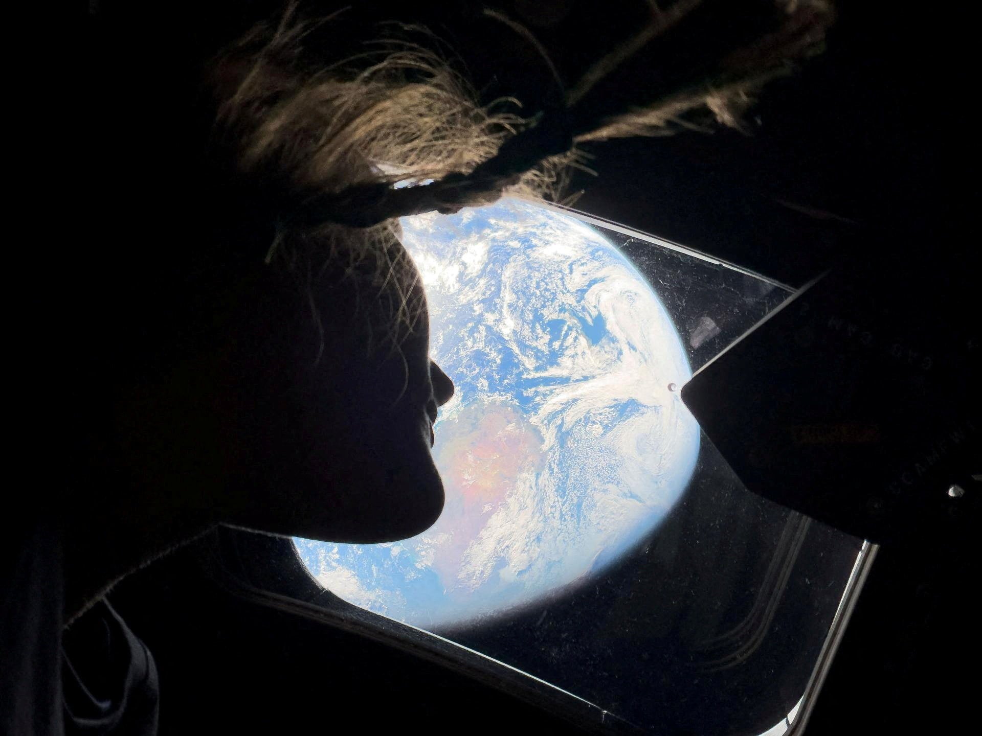 NASA astronaut and Artemis II mission specialist Christina Koch peers out of one of the Orion spacecraft's main cabin windows, looking back at Earth, as the crew travels towards the Moon April 2, 2026.  NASA/Handout via REUTERS. THIS IMAGE HAS BEEN SUPPLIED BY A THIRD PARTY. REFILE - CORRECTING YEAR FROM "2024" TO "2026".
