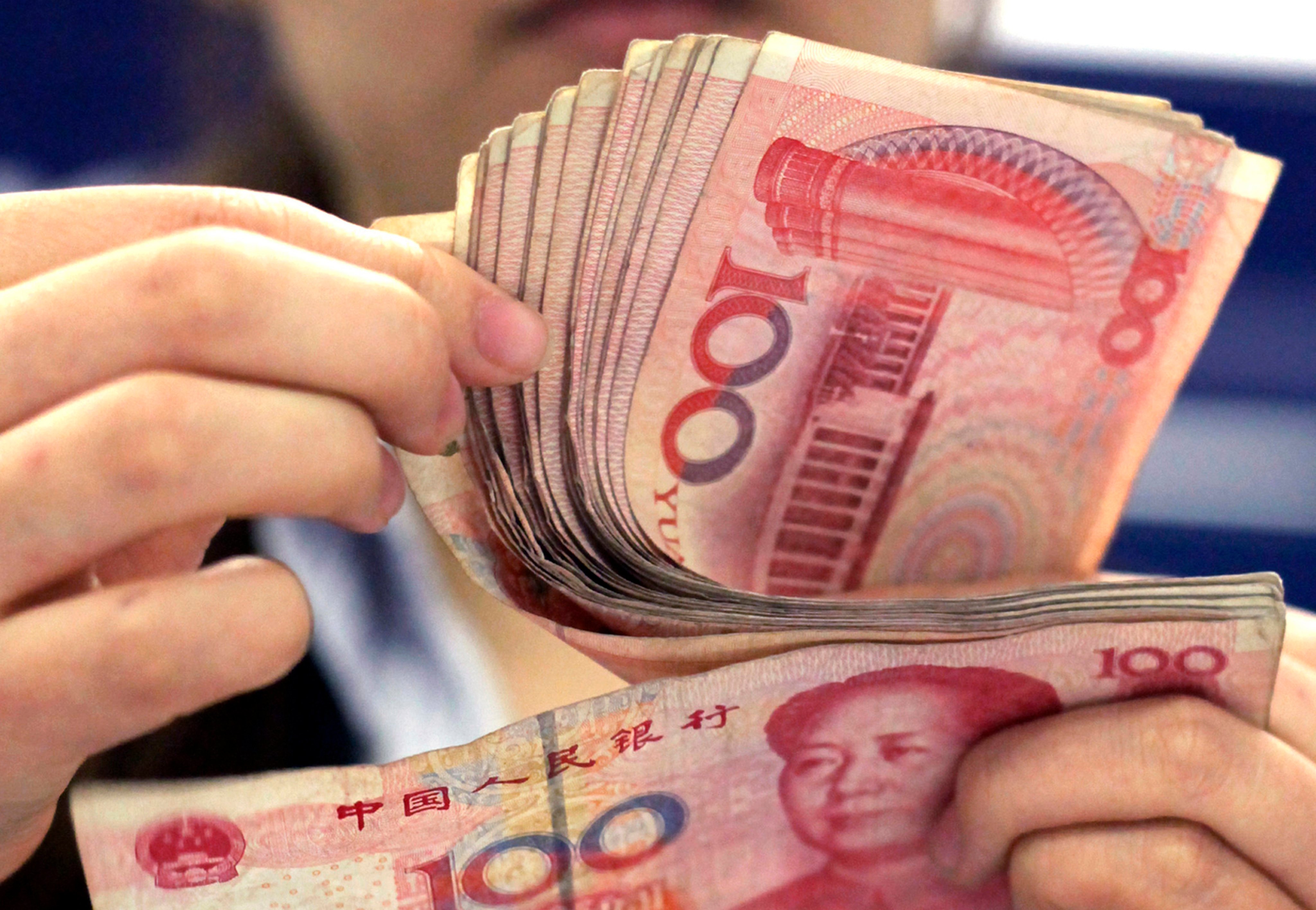 A bank clerk counts Chinese 100 yuan notes in Shanghai. Photo: AP