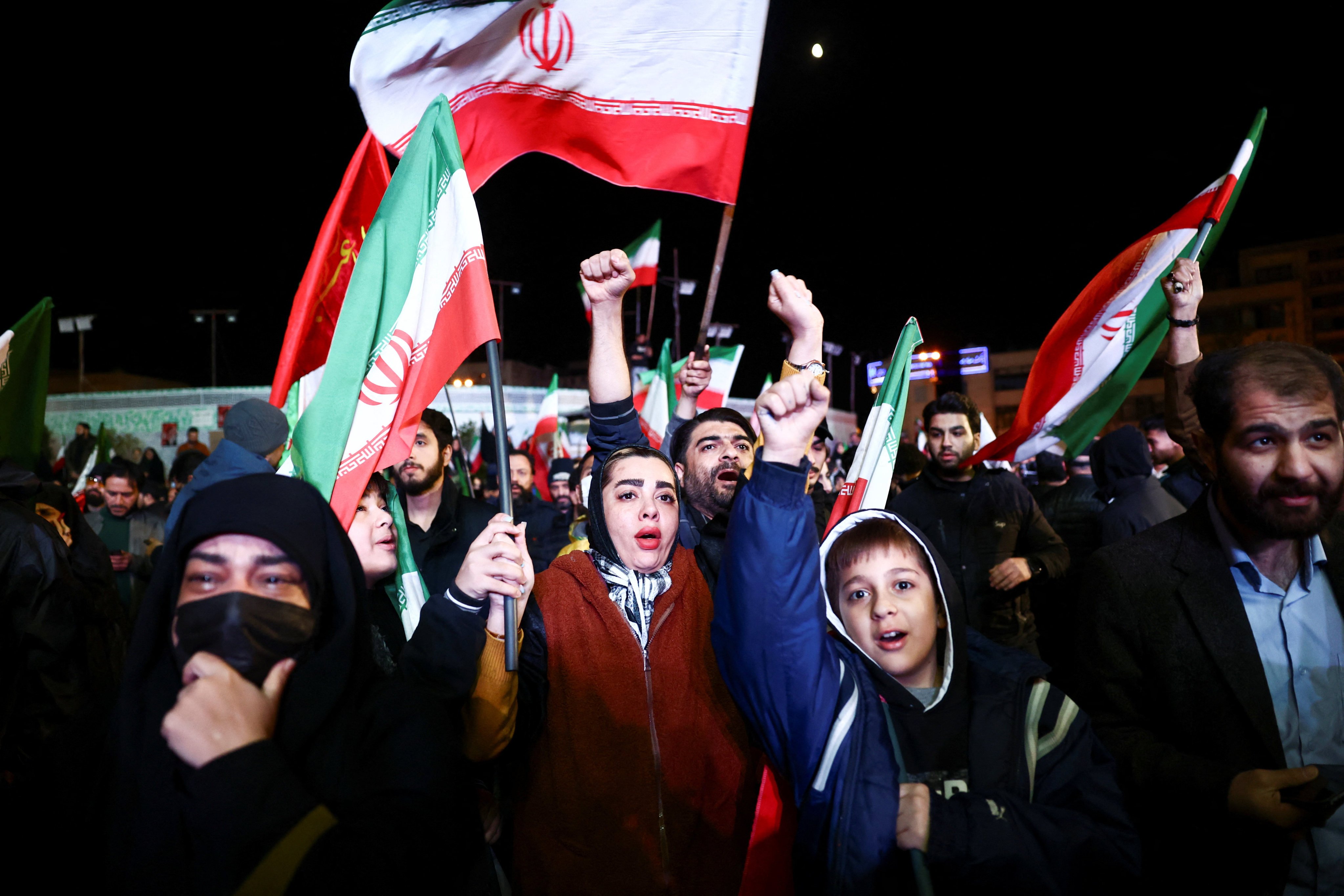People wave flags as they celebrate the announcement of a two-week ceasefire in the Iran war in Tehran on Wednesday. Photo: WANA/Reuters