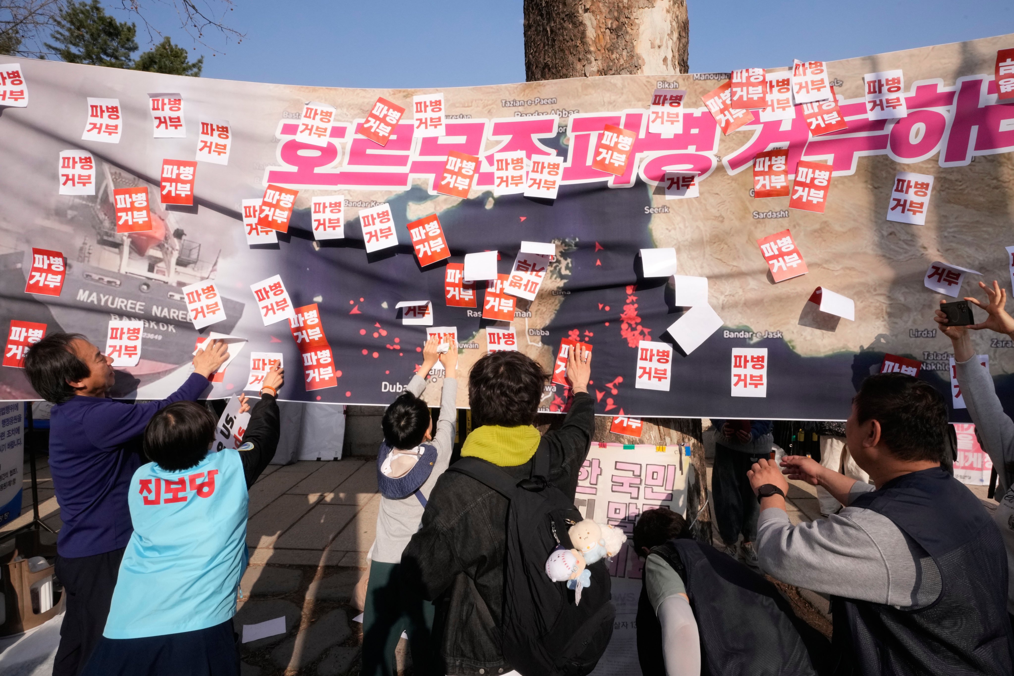 South Korean protesters attach stickers on a banner showing the Strait of Hormuz during a rally  near the presidential office in Seoul on March 28. The letters read “Refuse sending troops to Hormuz!” Photo: AP