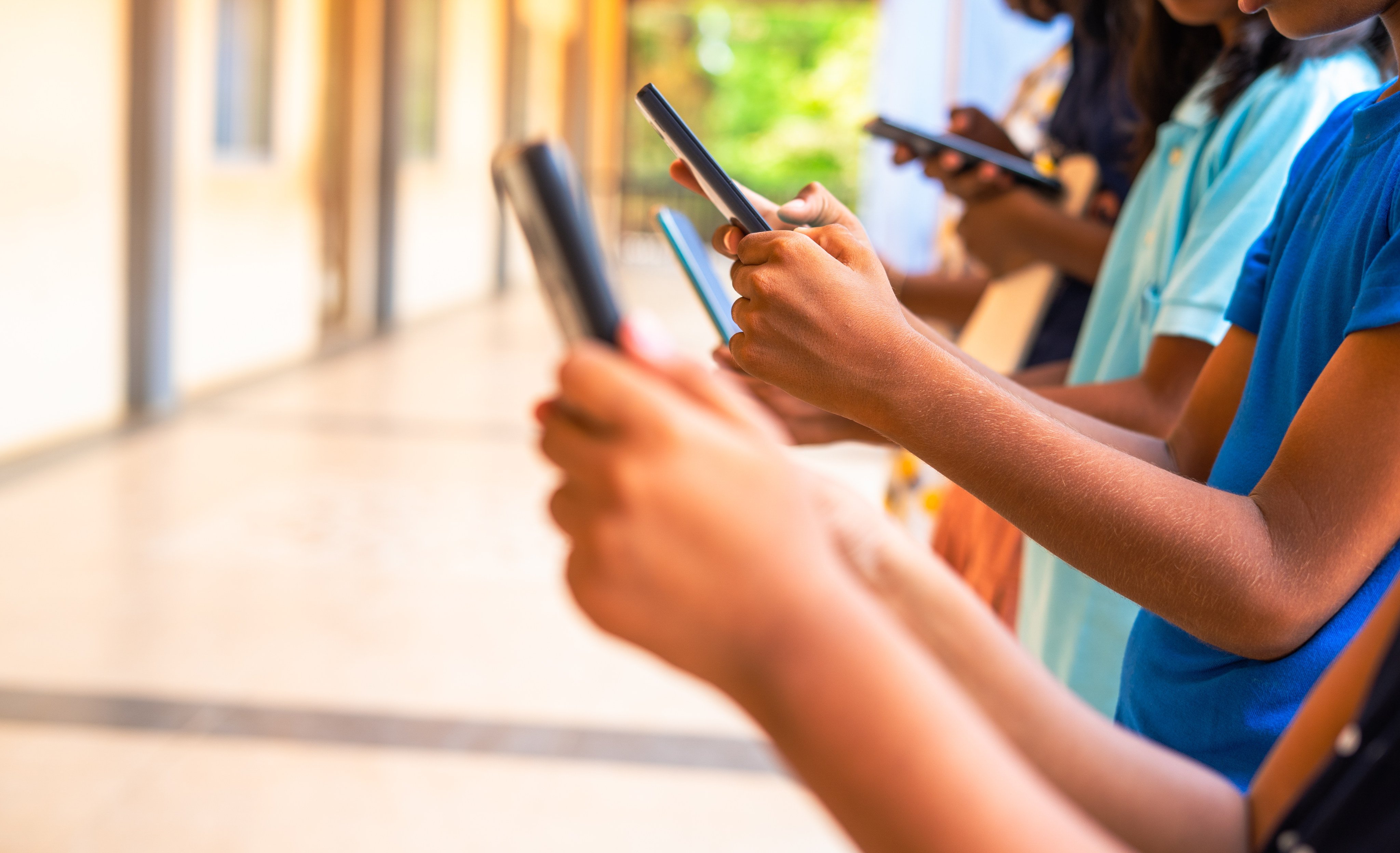 A group of children with mobile phones, all glued to their screens. Photo: Getty Images