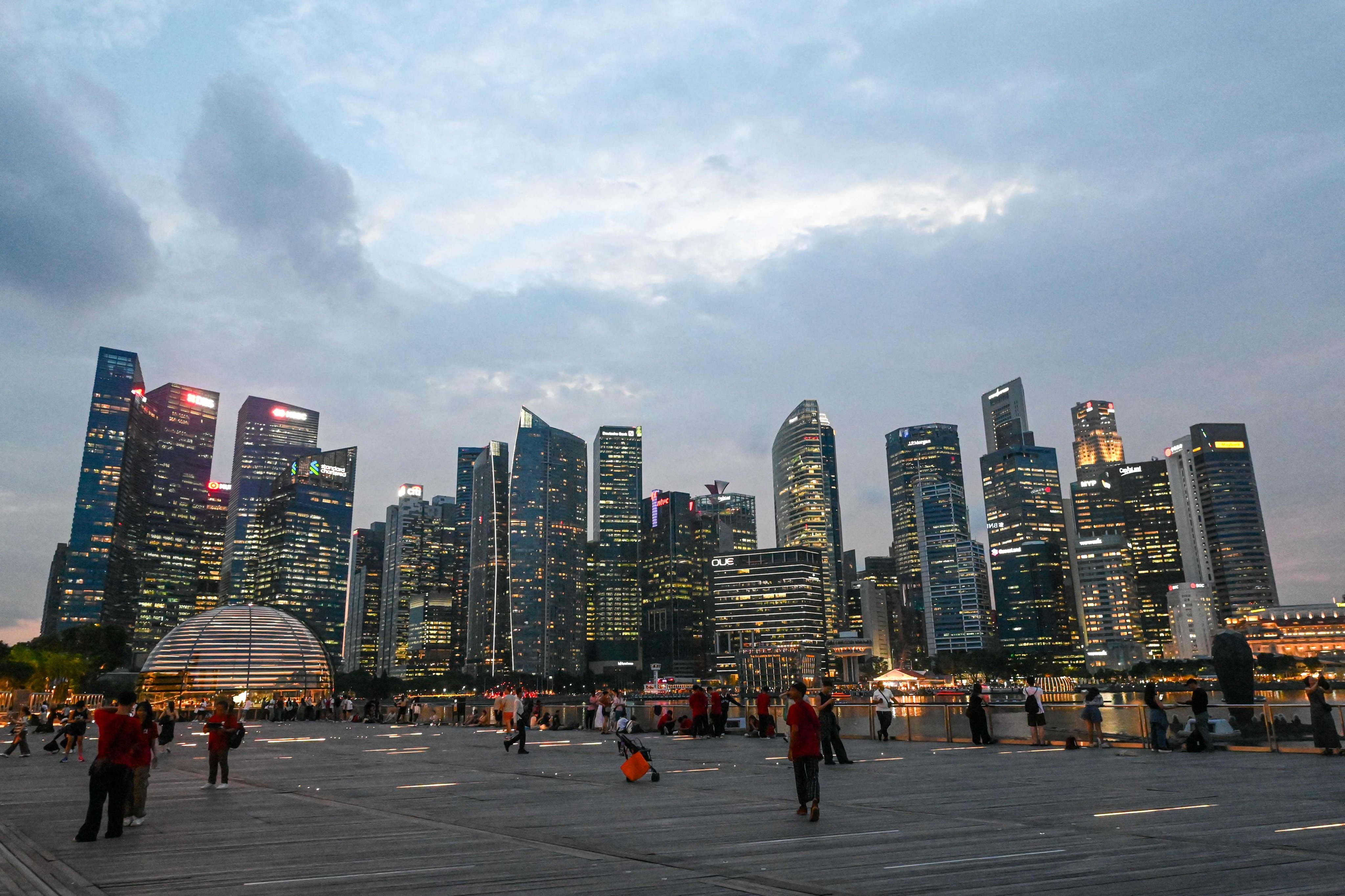 People gather along the boardwalk in front of the skyline at Marina Bay in Singapore. Photo: AFP