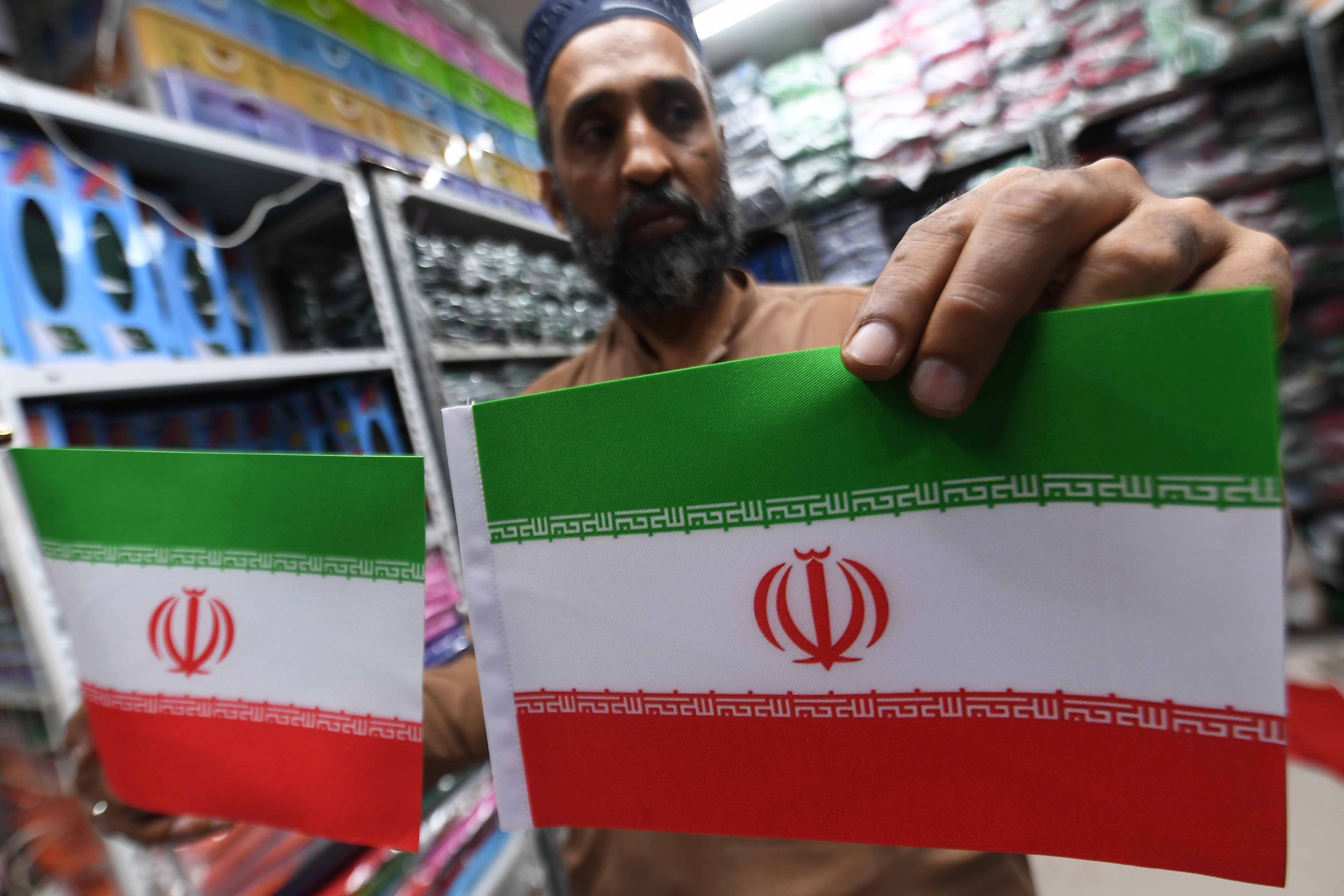 A shopkeeper displays Iranian flags after the US-Iran ceasefire announcement in Karachi, Pakistan, on Thursday. Photo: EPA