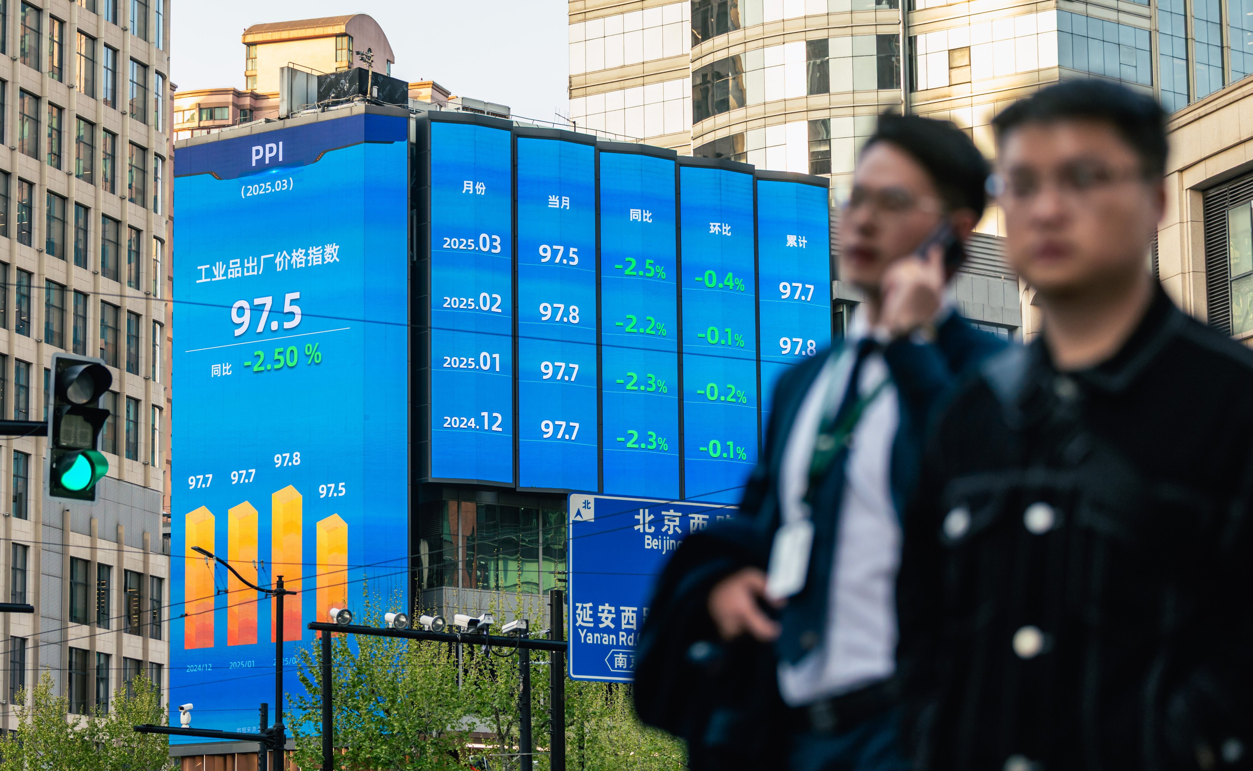 People walk near screens showing stock exchange and economic data in Shanghai, China. Photo: EPA