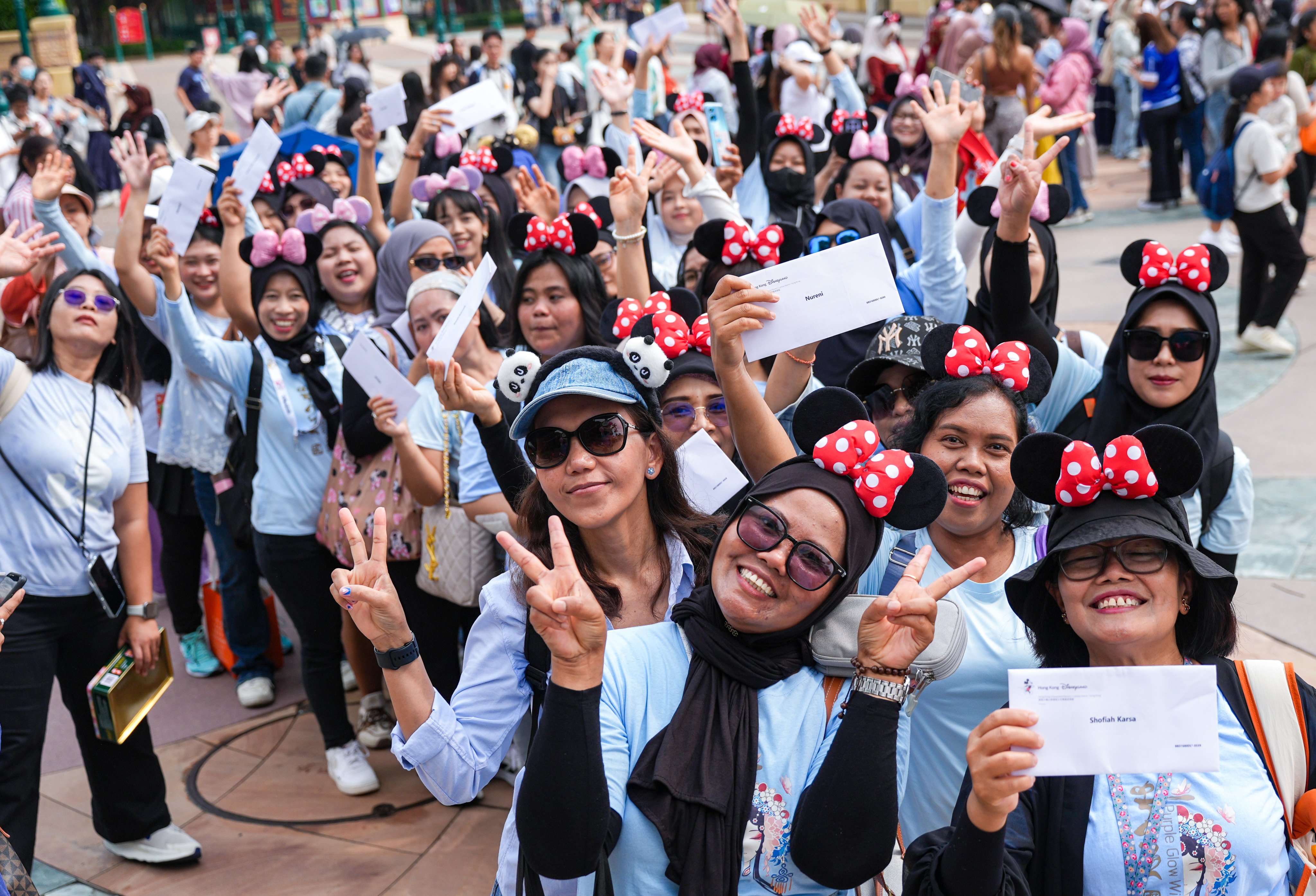 Domestic helpers pose for a photo with their free tickets to Hong Kong Disneyland. Photo: Eugene Lee