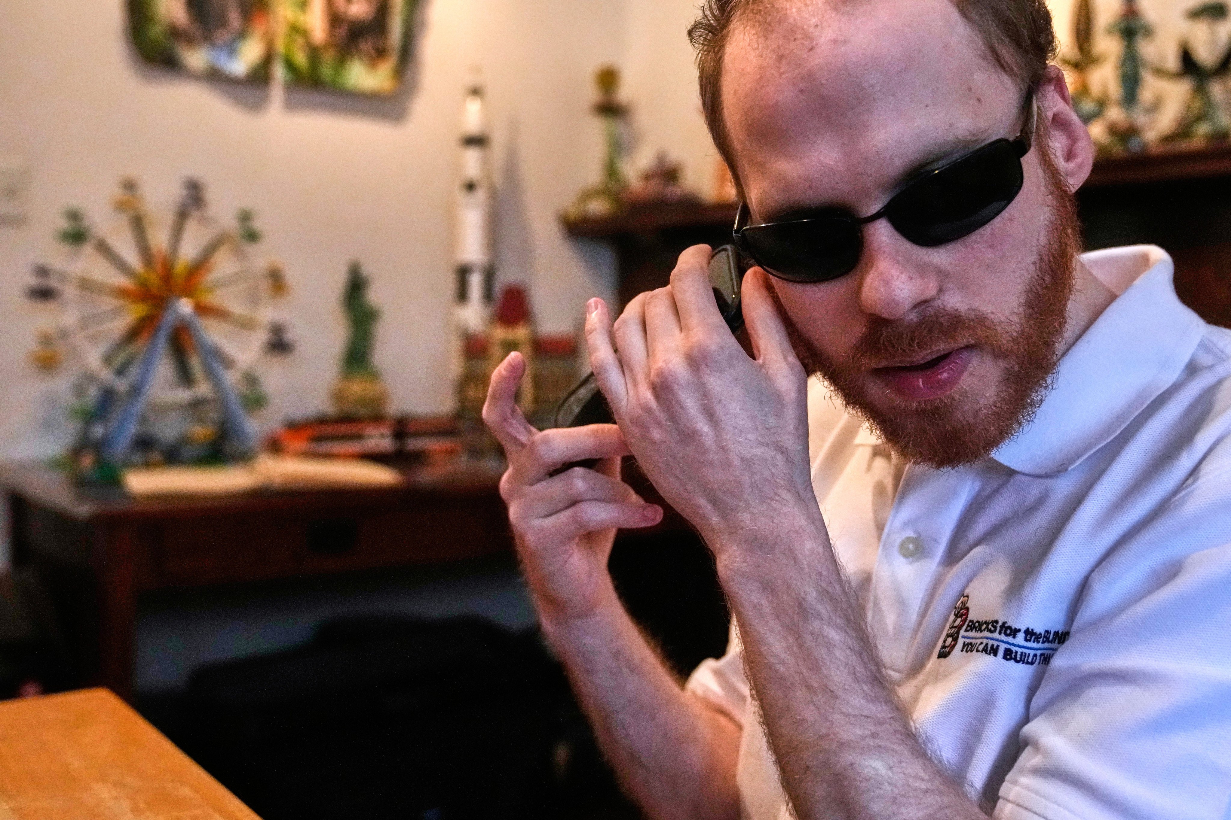 Matthew Shifrin, the founder of Bricks for the Blind, listens to directions on his phone while building a LEGO gumball machine. Photo: AP