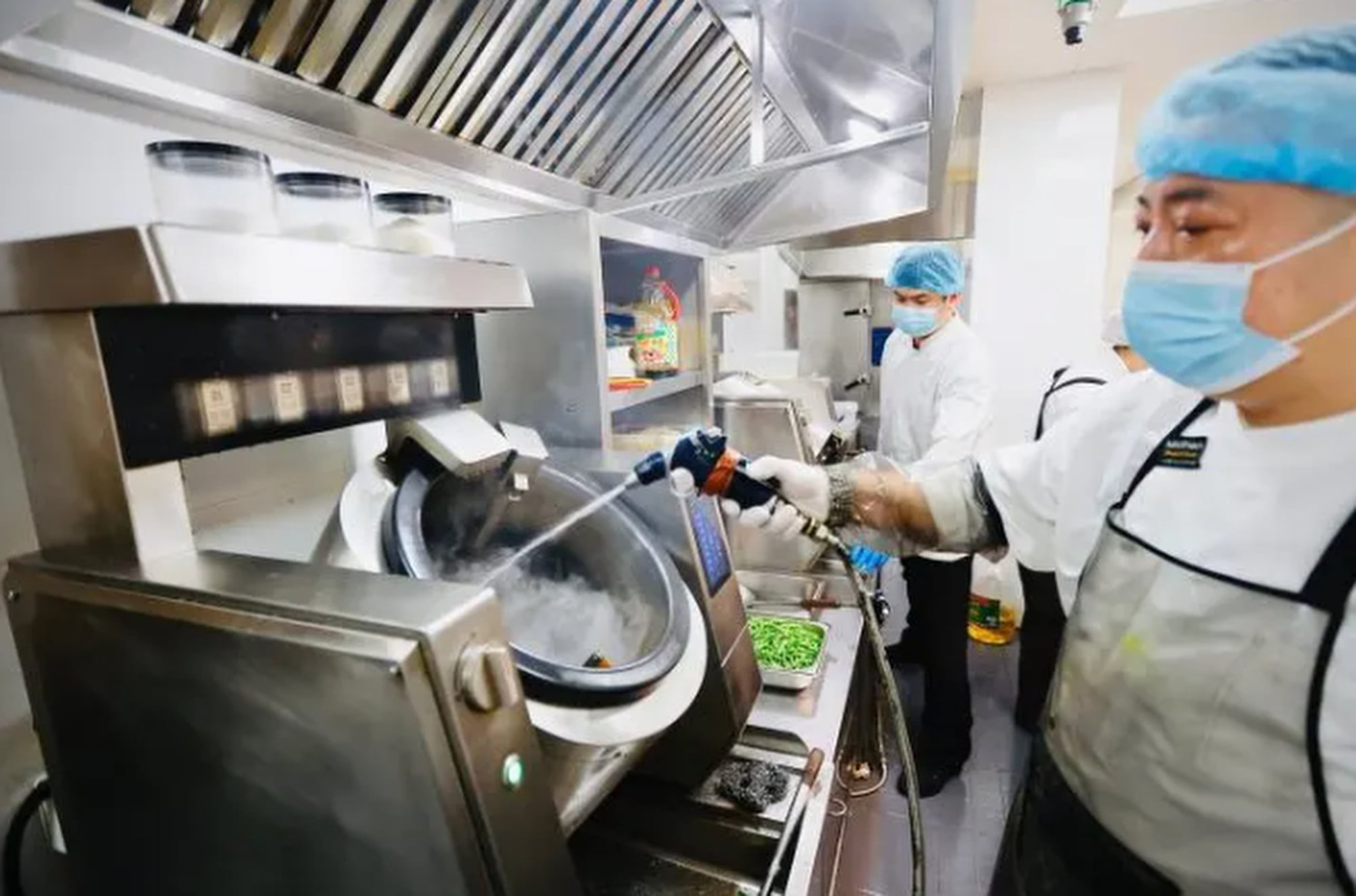 A masked member of restaurant staff cleans a machine using a jet of water. Photo: QQ.com A masked member of restaurant staff cleans a machine using a jet of water. Photo: QQ.com