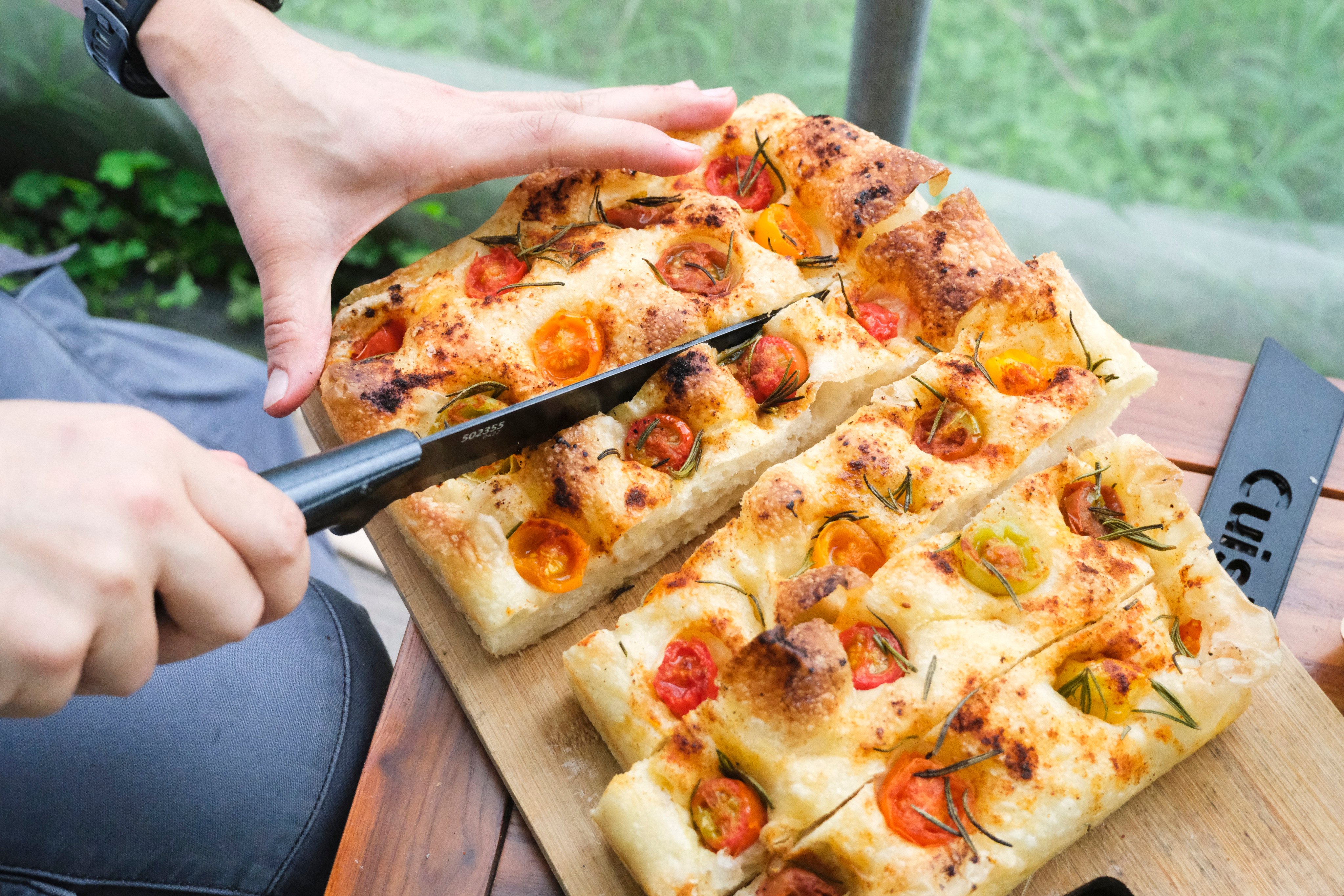 A fresh loaf of cherry tomato and rosemary focaccia baked by  Formless Daily, an artisanal small-batch bakery that uses ingredients from Hong Kong farms, is cut at a farm-to-table experience at Blue Girl Organic Farm in Tai Tong. Photo: Hei Kiu Au