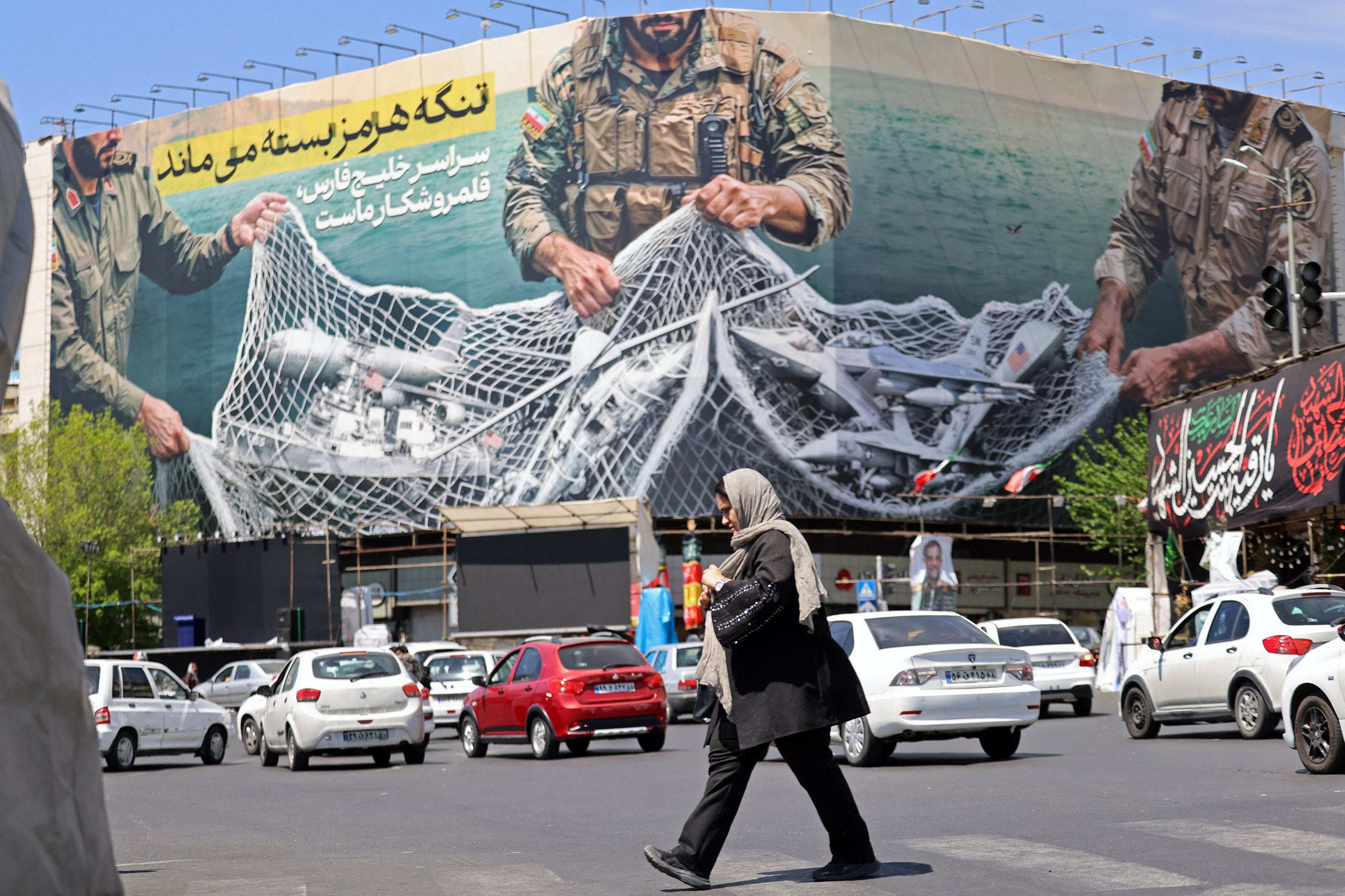 A woman walks past a giant billboard reading “The Strait of Hormuz remains closed” at Revolution Square in Tehran, Iran. Photo: TNS