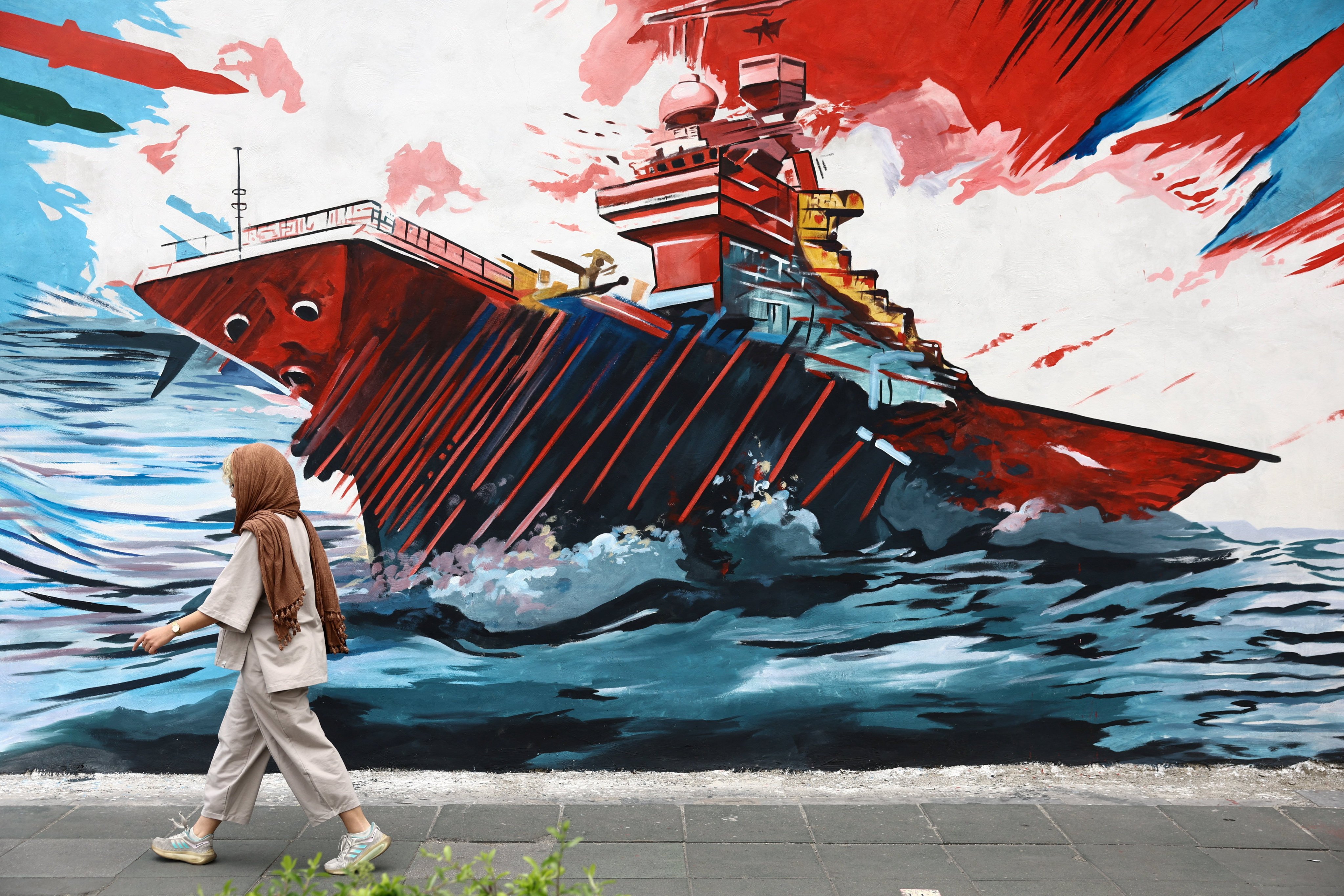 A woman walks next to an anti-US mural on a street in Tehran, Iran, on Sunday. Photo: WANA via Reuters