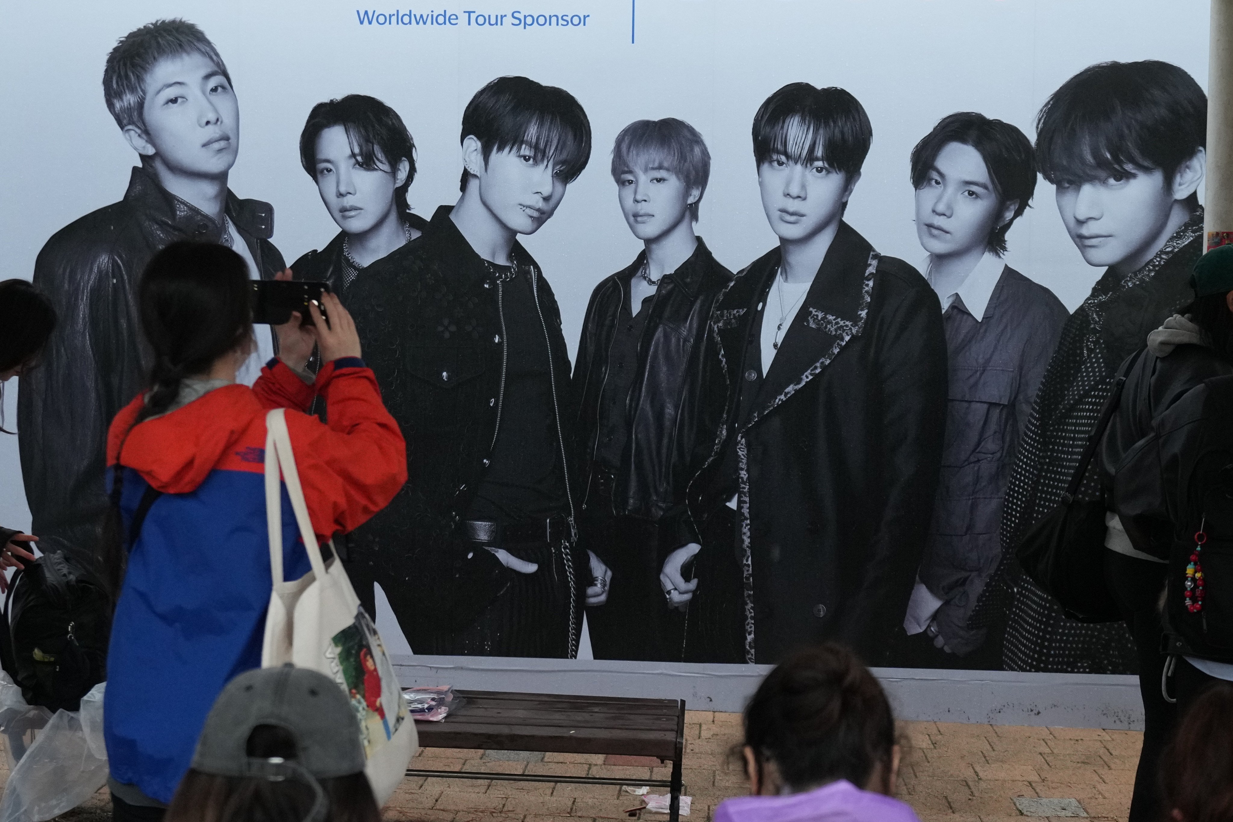 A BTS fan takes a photo of the band’s poster outside the stadium before the “Arirang” World Tour concert in Goyang, South Korea, on April 9. Photo: AP