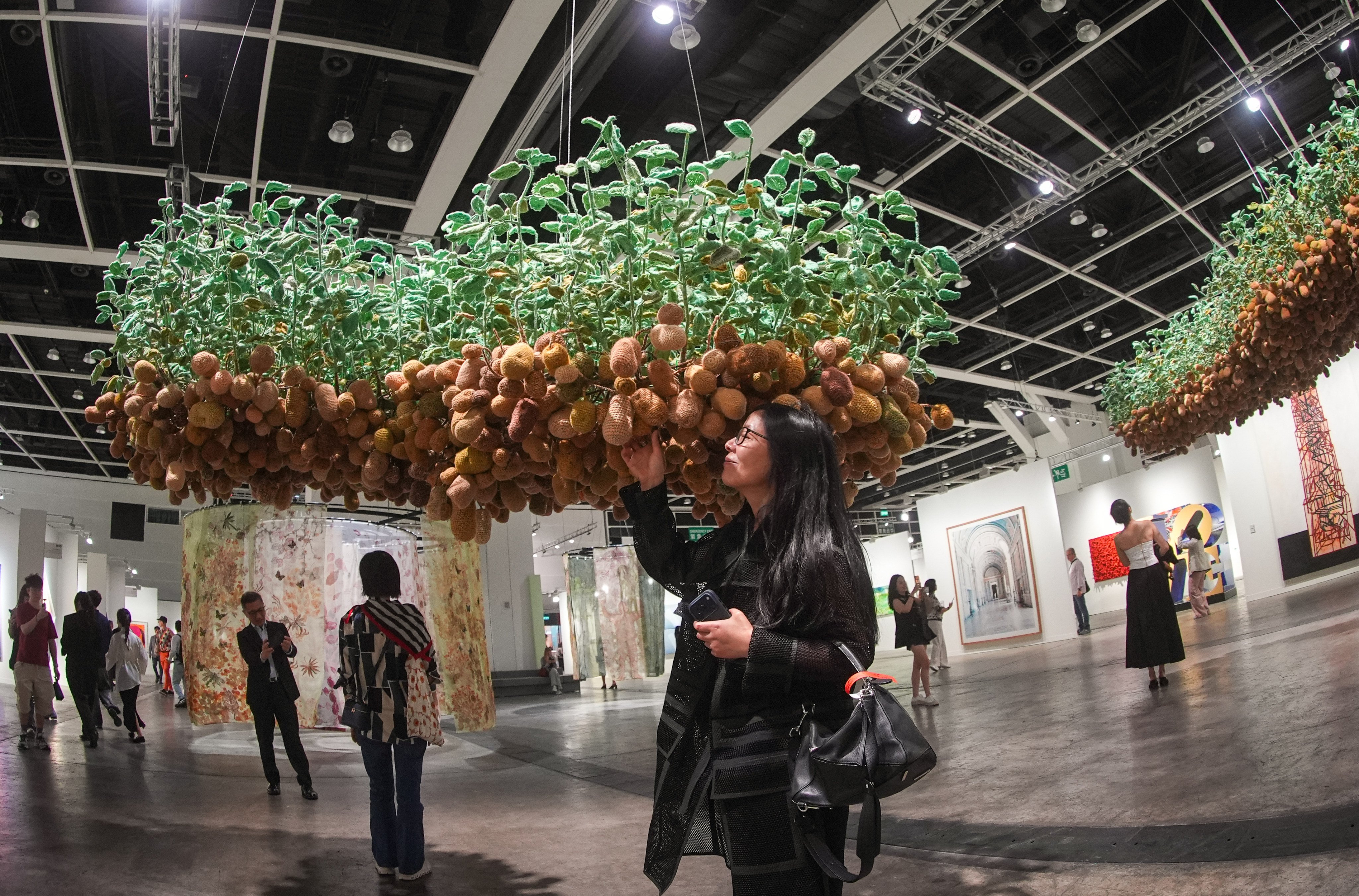 A visitor poses for a photo with Hu Yinping’s Potatoes Grow on Trees at Art Basel at Hong Kong Convention and Exhibition Centre in Wan Chai on March 25. Photo: Eugene Lee