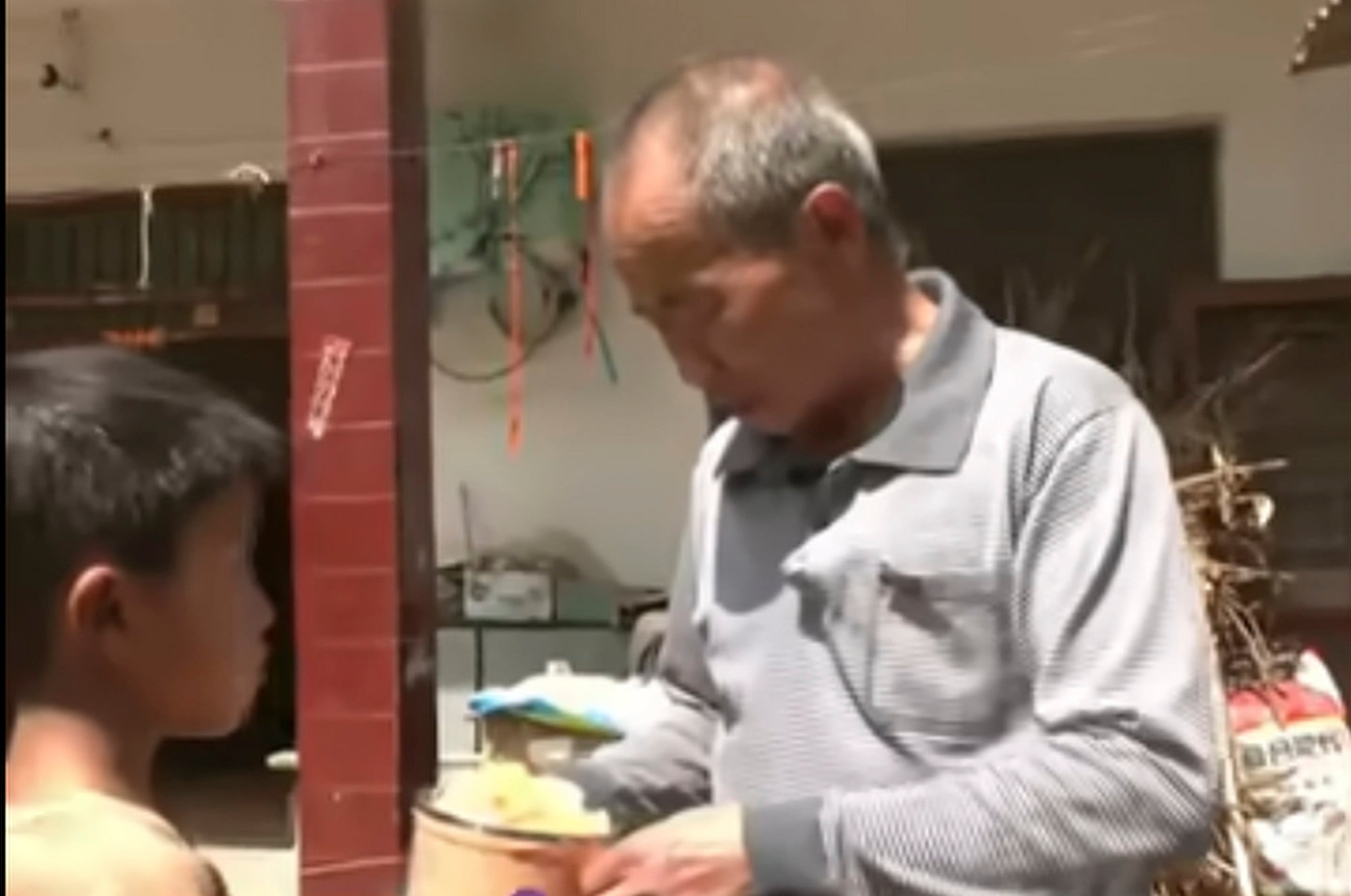 Zichen gives his grandfather some food. The youngster worries that if his grandpa does not eat well he might die. Photo: Weibo