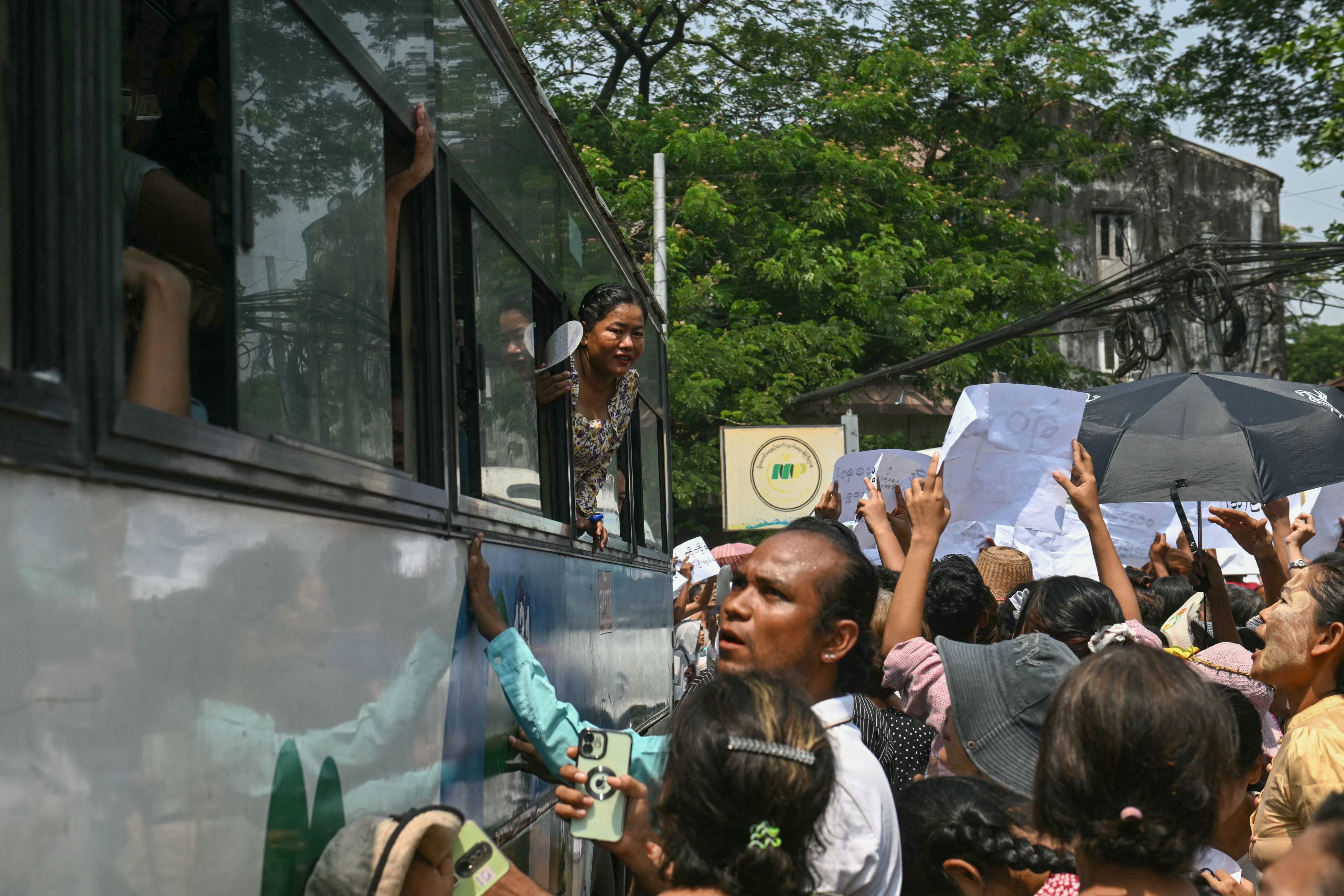 Released prisoners look out from a bus after it came out from Insein Prison, as relatives gather around it searching for their loved ones, during an amnesty to mark Myanmar’s new year in Yangon on April 17, 2026. More than 4,300 prisoners were slated for release on April 17 to mark Myanmar’s Thingyan new year, one of the country’s many public holidays when forgiveness orders are regularly announced. (Photo by Sai Aung MAIN / AFP)