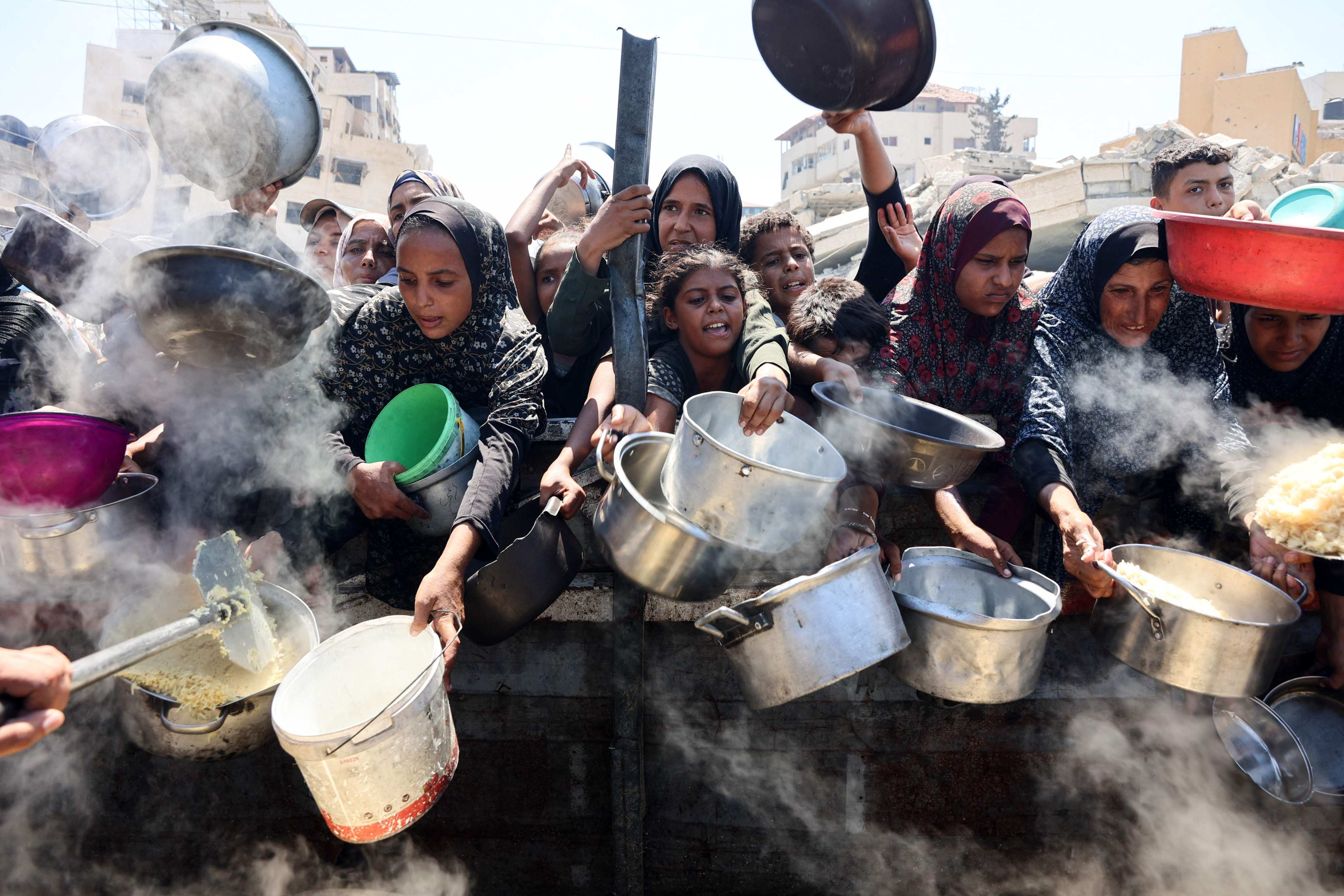 Palestinian women and girls elbow their way to receive cooked rice from a charity kitchen in Gaza City. Photo: AFP