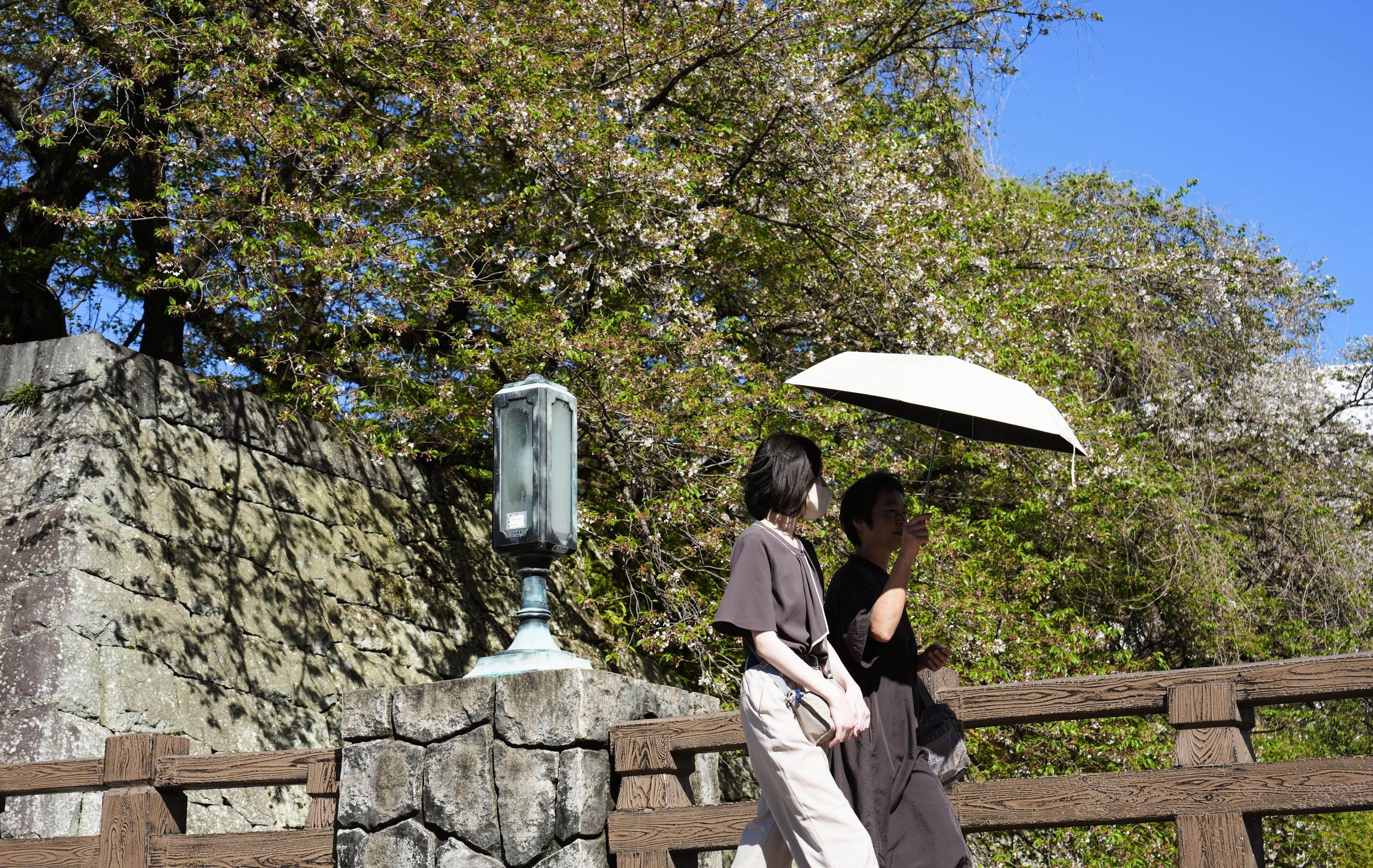People walk under a parasol in Shizuoka, Japan, where temperatures exceeded 30 degrees Celsius, on April 11. Photo: Kyodo