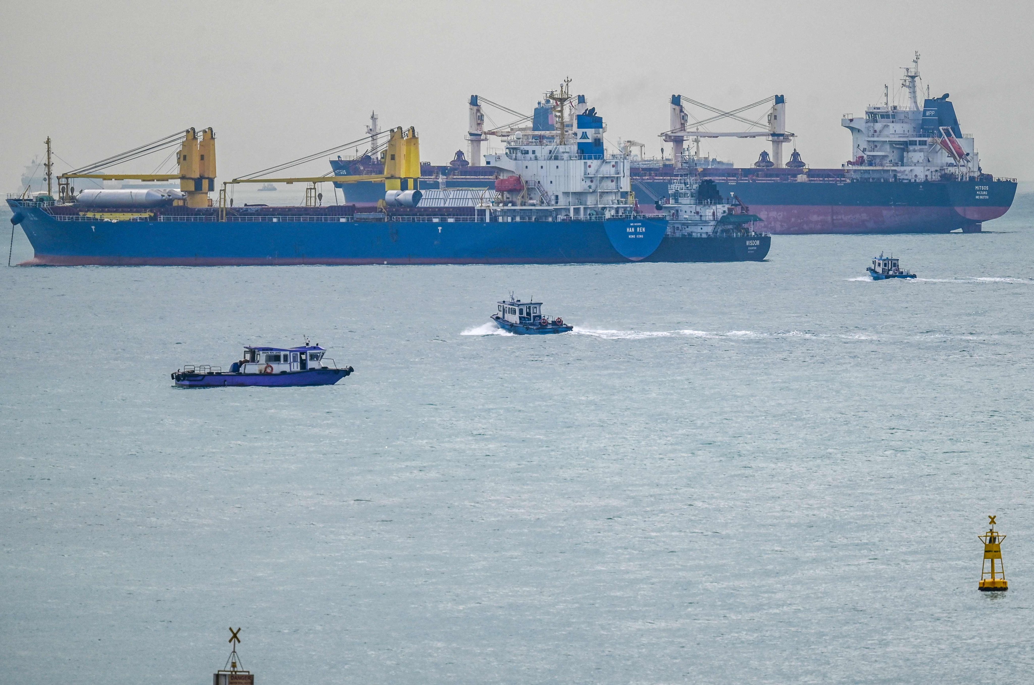 Small boats sail beside vessels anchored in the Strait of Singapore on Tuesday. Photo: AFP