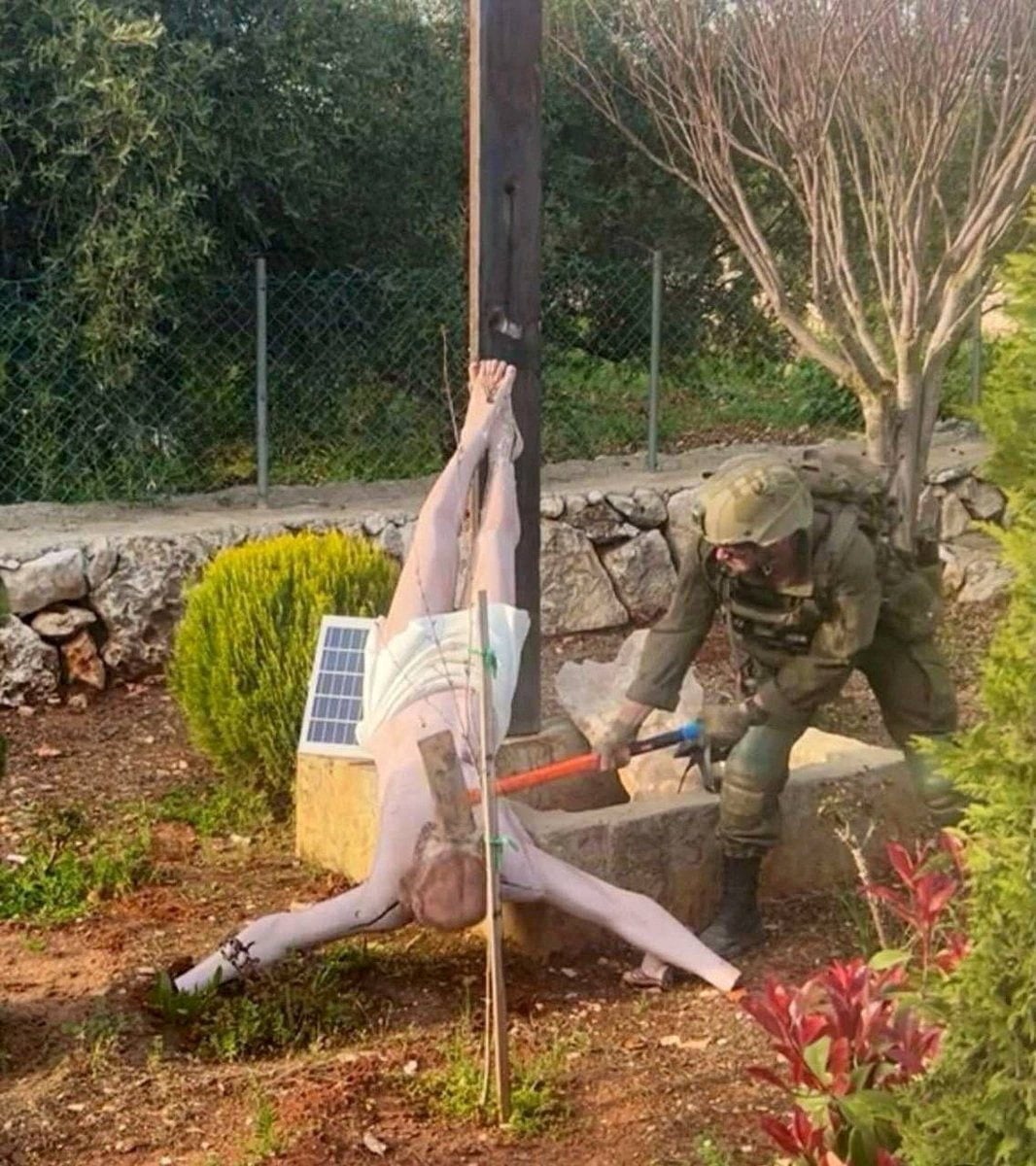 An Israeli soldier damages the head of a statue of Jesus, in Debel, Lebanon. Photo: Social media via Reuters
