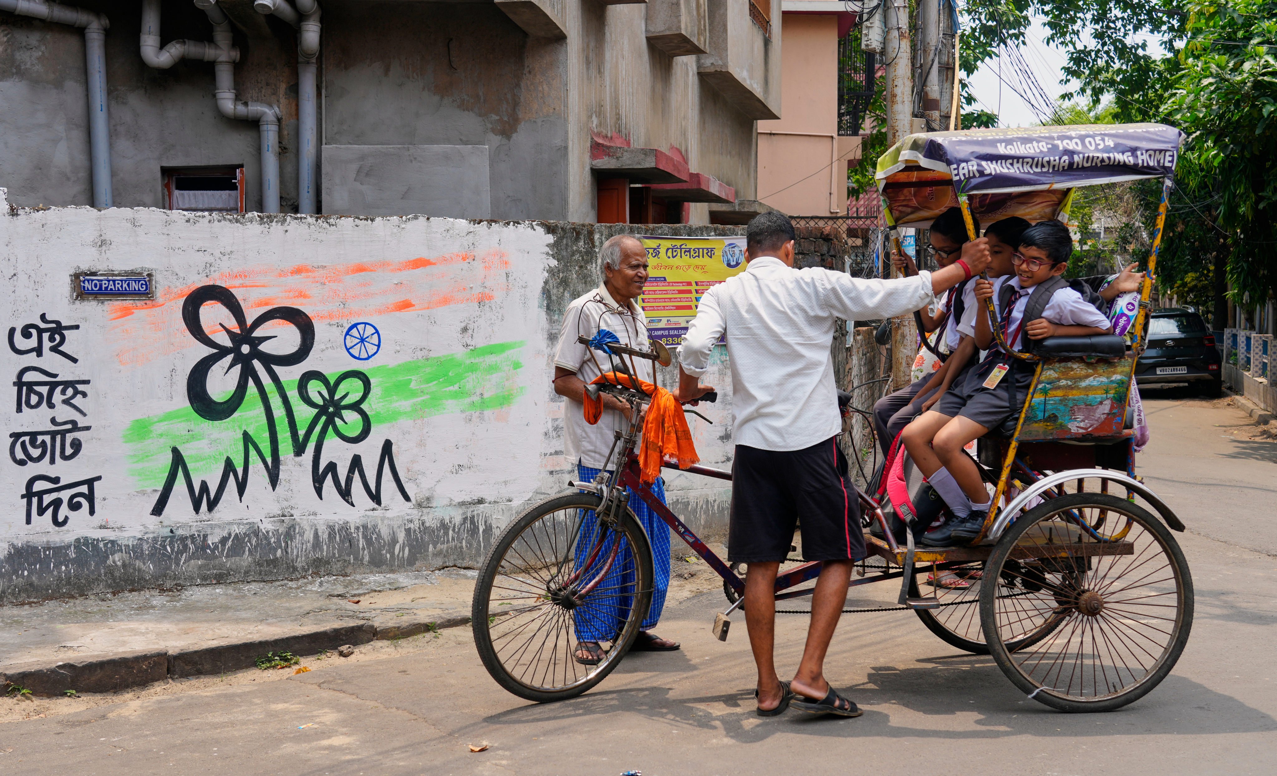 A tricycle rider transports school children home in Kolkata on Friday. Photo: AP