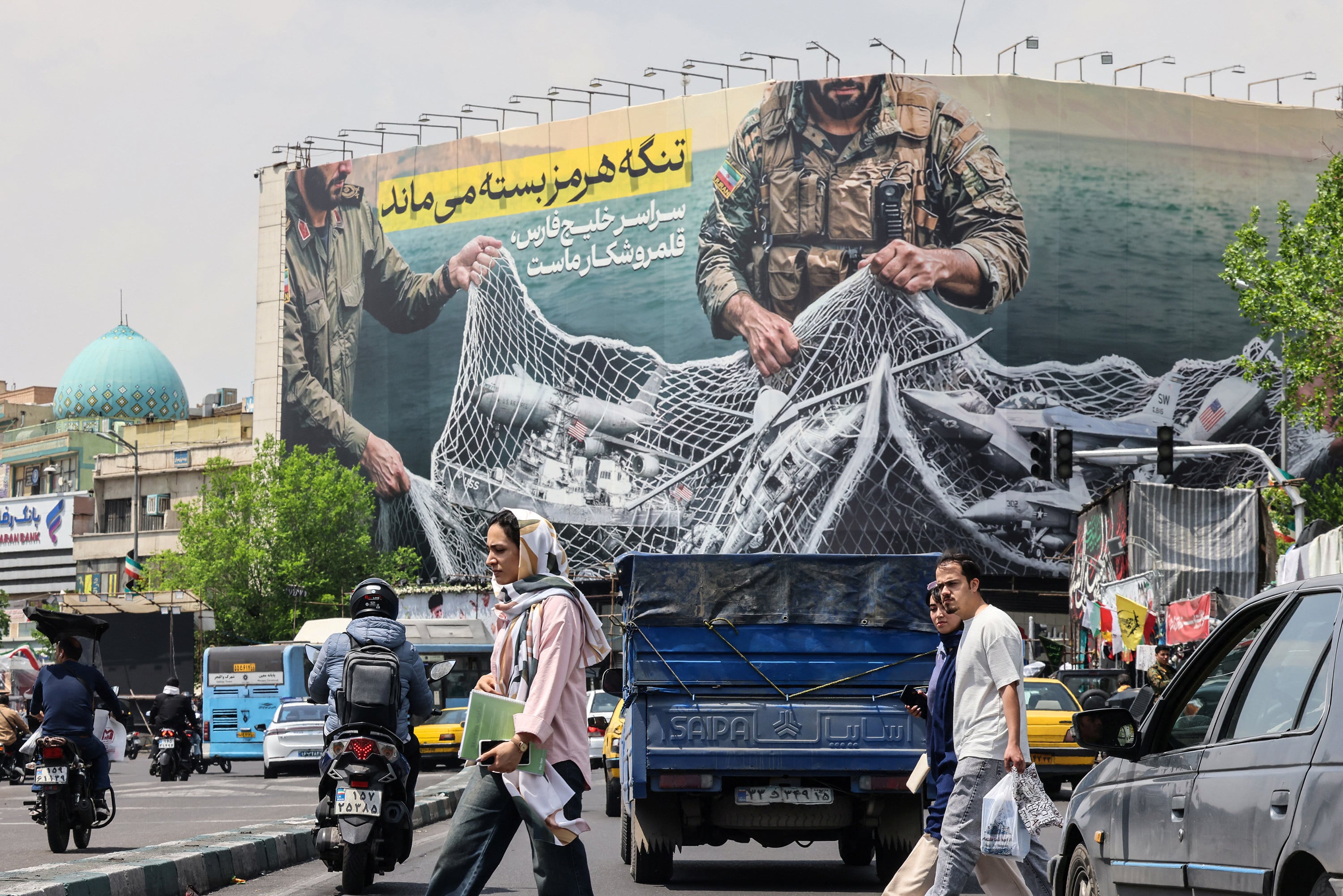 Iranian walks past a billboard reading “The Strait of Hormuz remains closed” at the Revolution Square in Tehran on Wednesday. Photo: AFP/Getty Images/TNS
