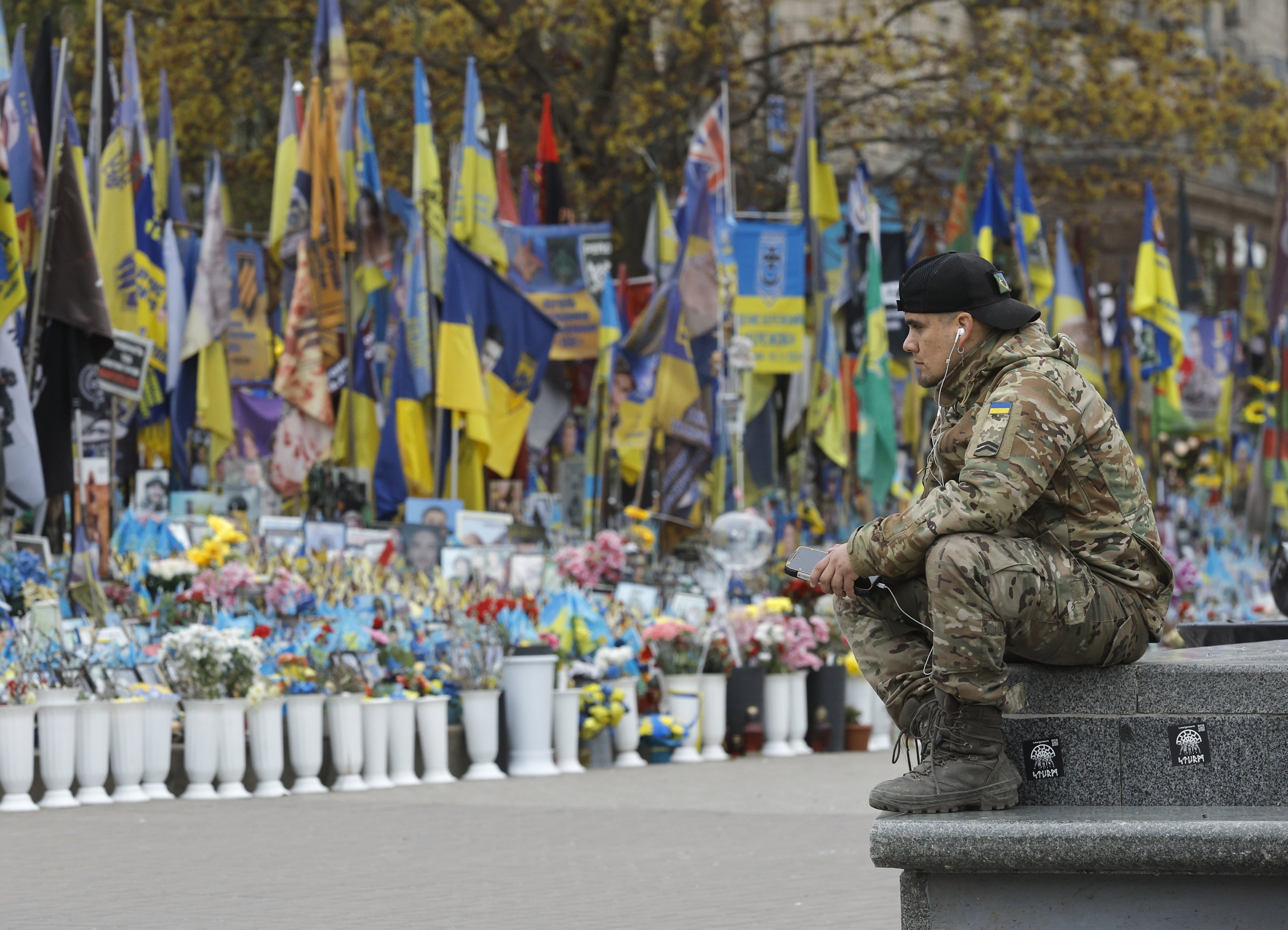 A man in military uniform sits near a makeshift memorial dedicated to the fallen Ukrainian soldiers and international volunteers in Independence Square in Kyiv, Ukraine on April 20, 2026. Photo: EPA