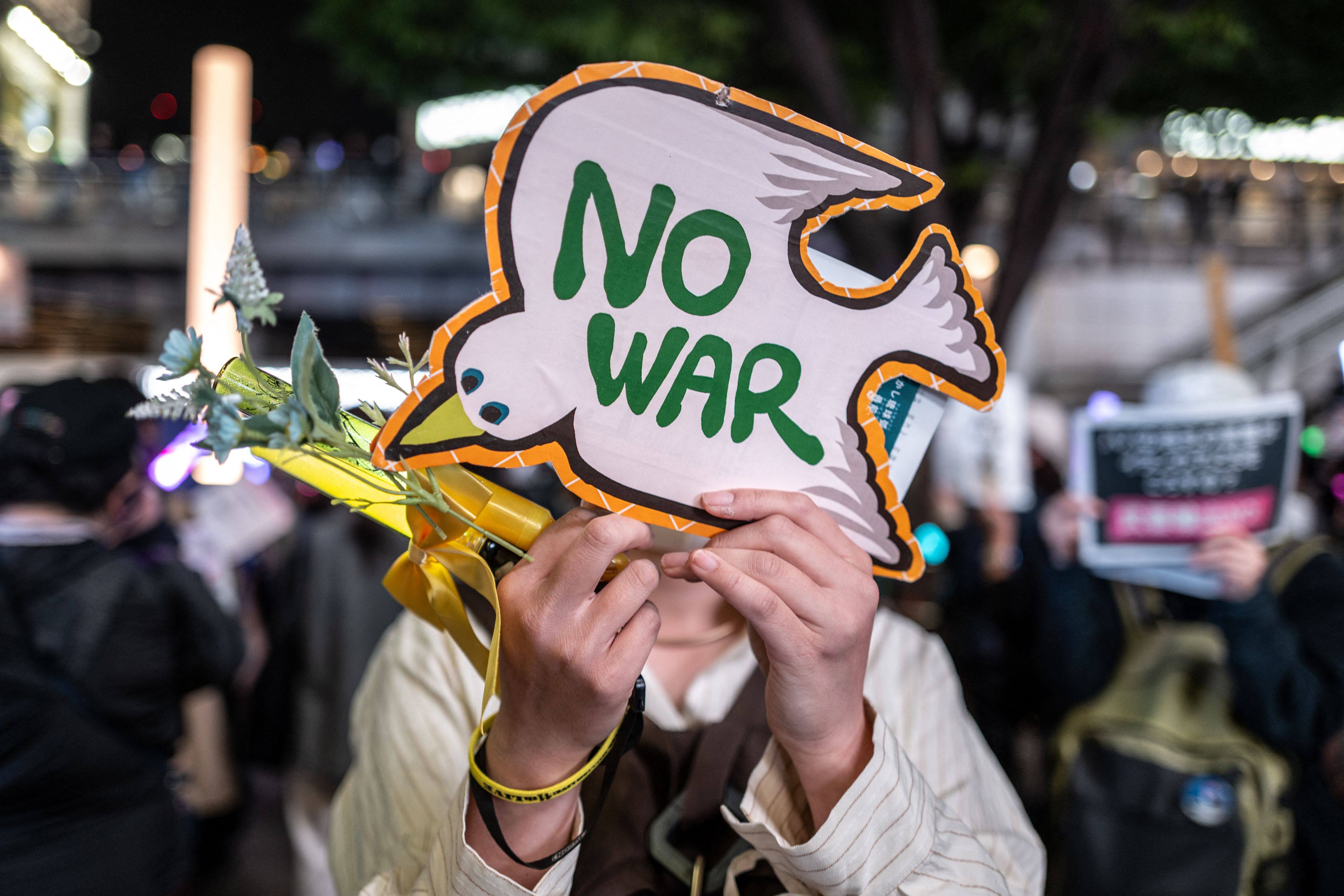 A participant holds a placard reading “No War” during a protest against Japan’s lethal arms export rule change, in Tokyo’s Shinjuku district on Friday. Photo: AFP
