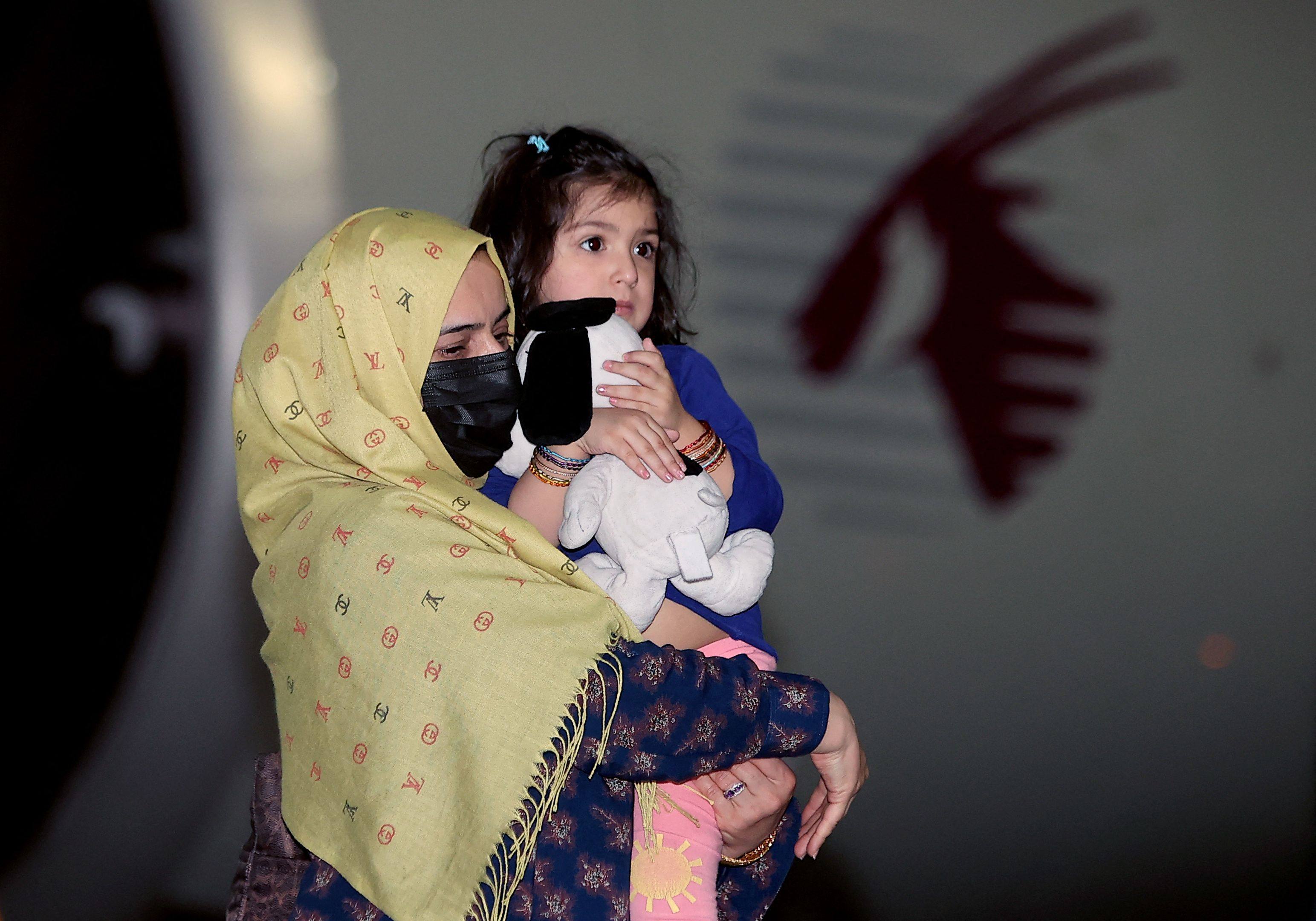 A woman carries a child as they arrive in Qatar with other evacuees from Afghanistan in  2021, following the US withdrawal. Photo: AFP