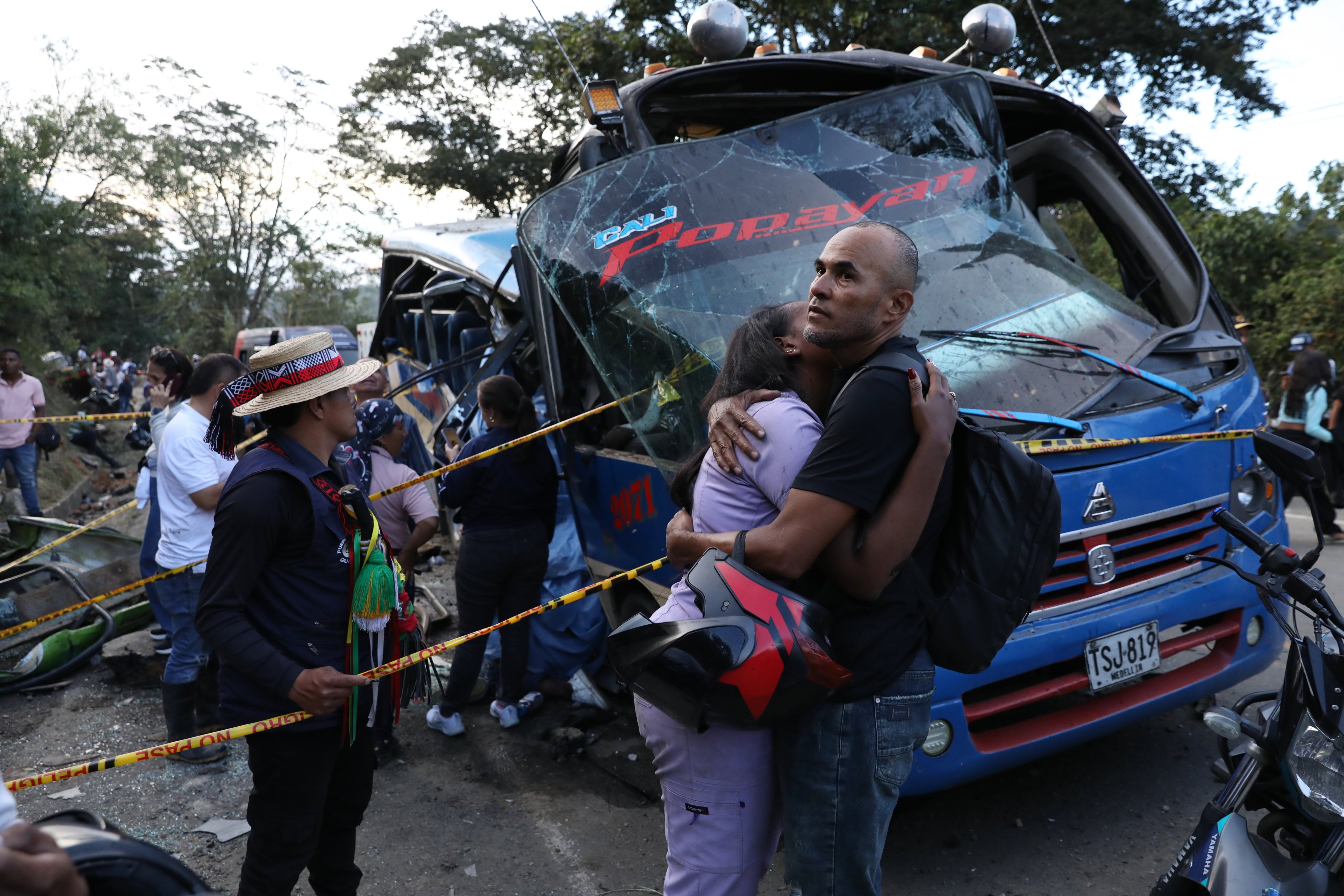 Relatives of victims embrace in front of a bus hit by an explosive device in Cajibio, Colombia, on Saturday. Photo: AP