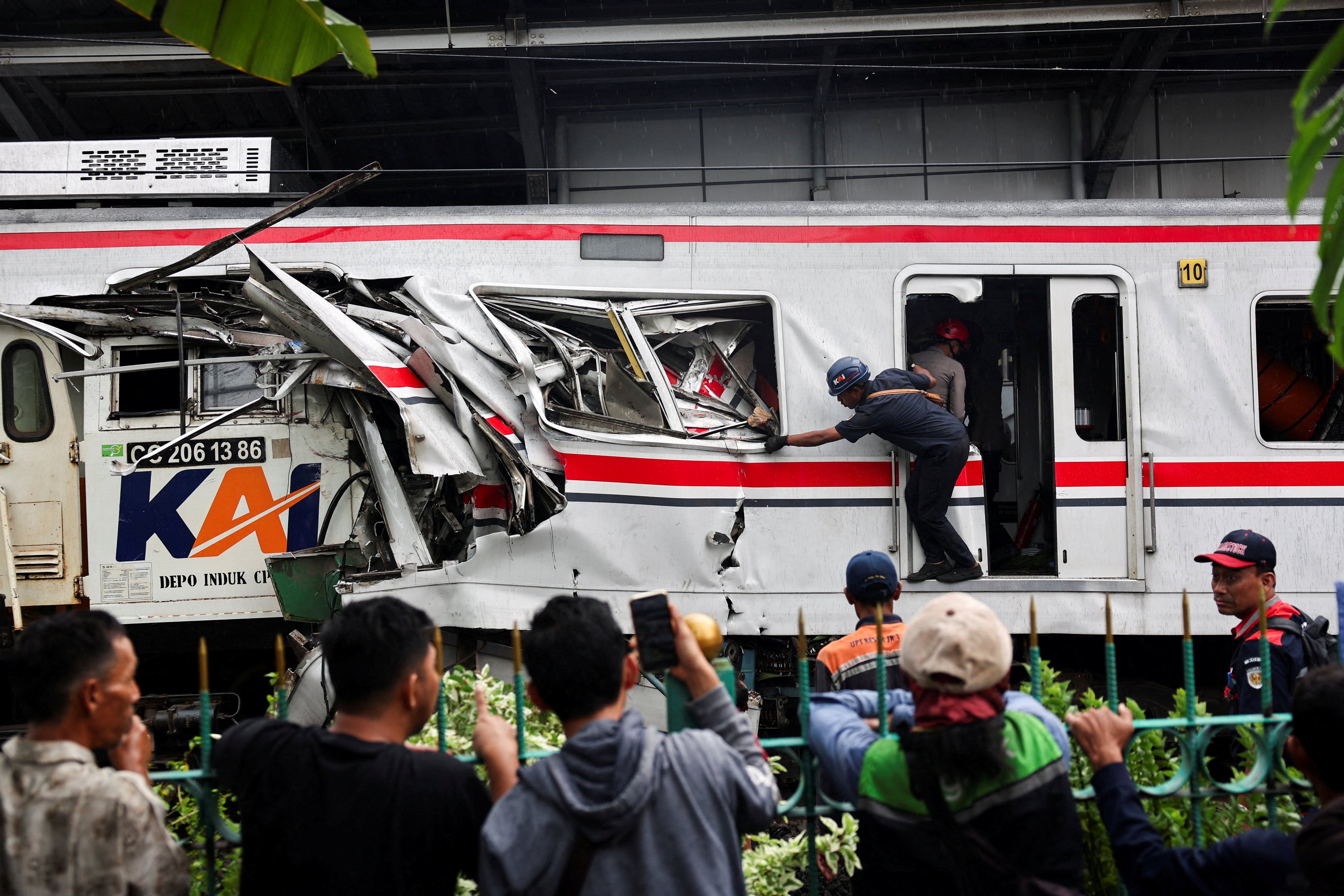 People watch as a technician works at the site after a deadly collision between a commuter line train and a long-distance train, in Bekasi, on the outskirts of Jakarta, Indonesia, April 28, 2026. REUTERS/Willy Kurniawan     TPX IMAGES OF THE DAY
