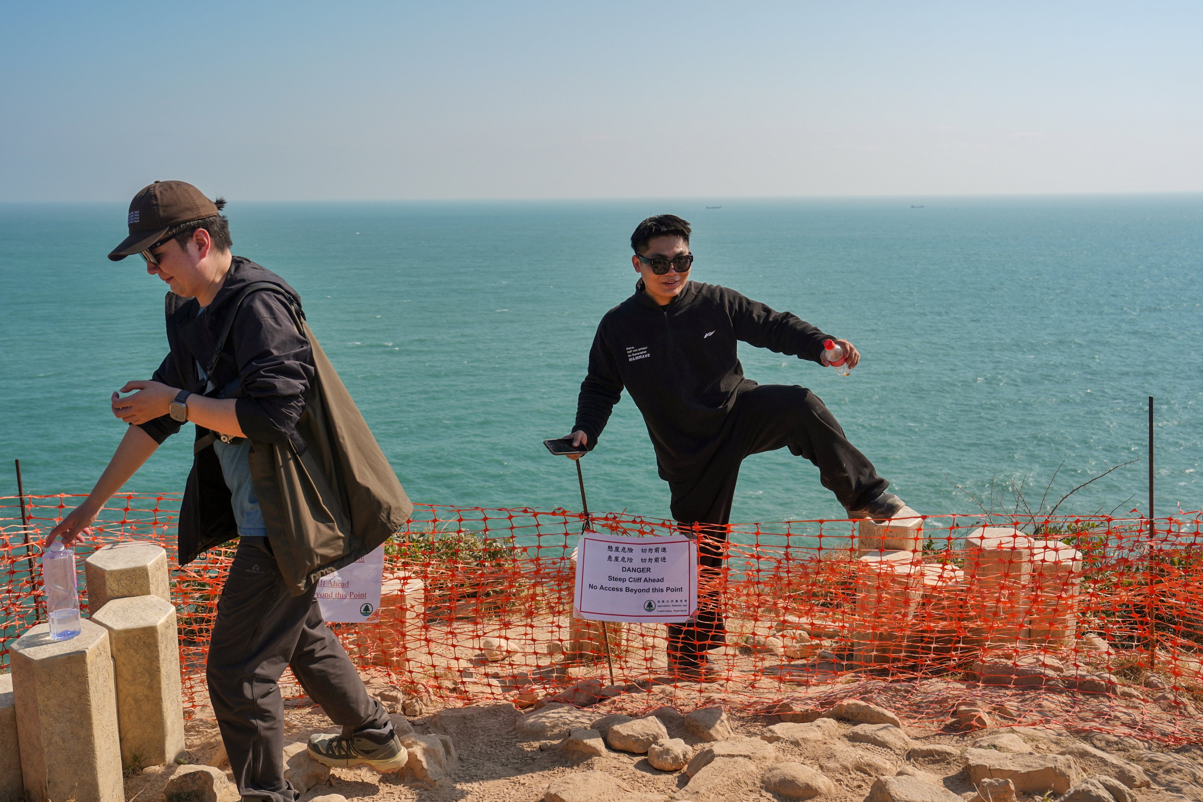 A man crosses a hazard warning boundary after taking pictures near the edge of a cliff on the way to the Po Pin Chau Viewing Platform at  High Island Reservoir’s East Dam on January 3. Photo: Elson Li
