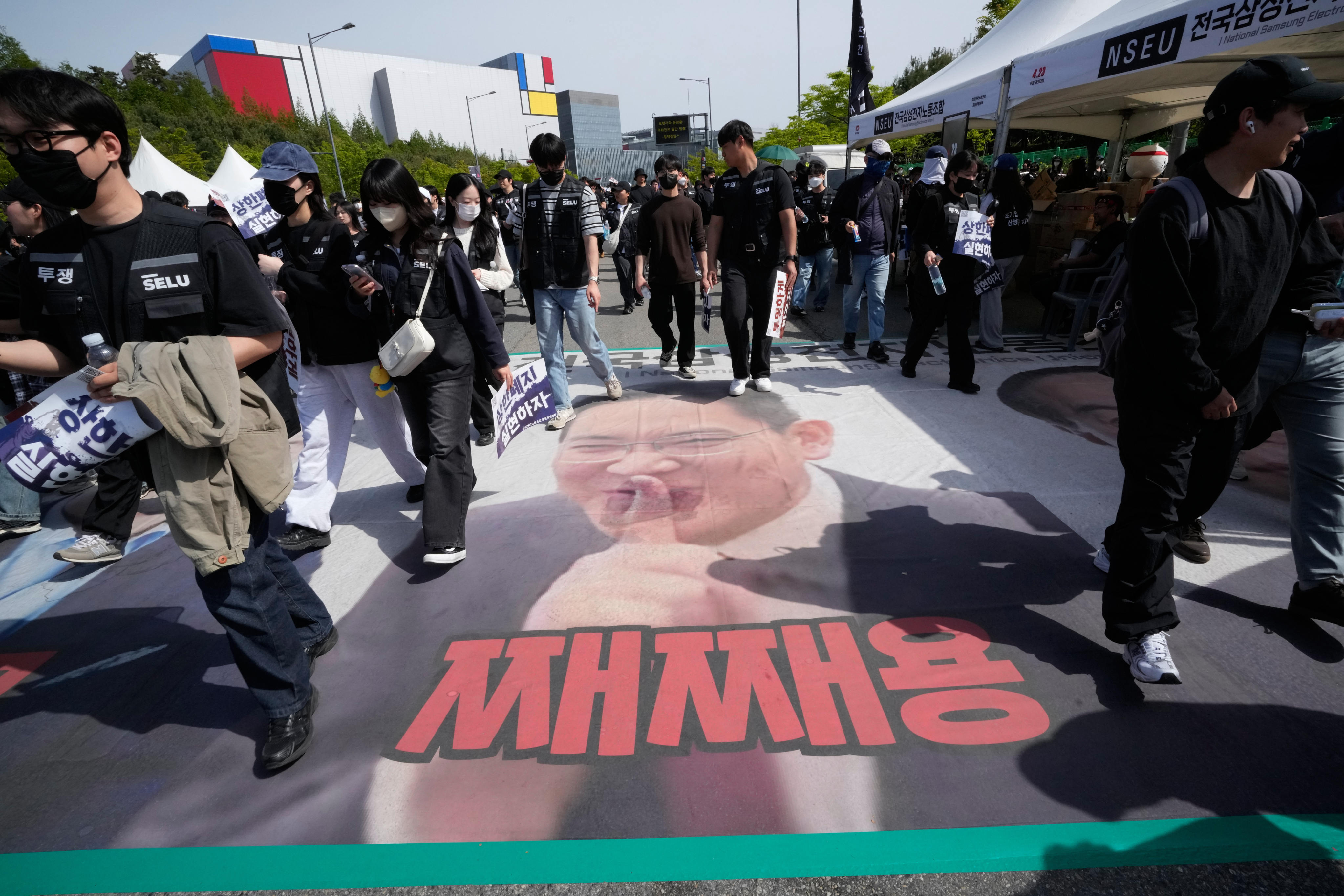 Members of the Samsung Electronics trade union walk on a banner showing a picture of Samsung Electronics chairman Jay Y. Lee after a rally demanding higher bonuses at its computer chip complex in Pyeongtaek, South Korea, on Thursday. Photo: AP