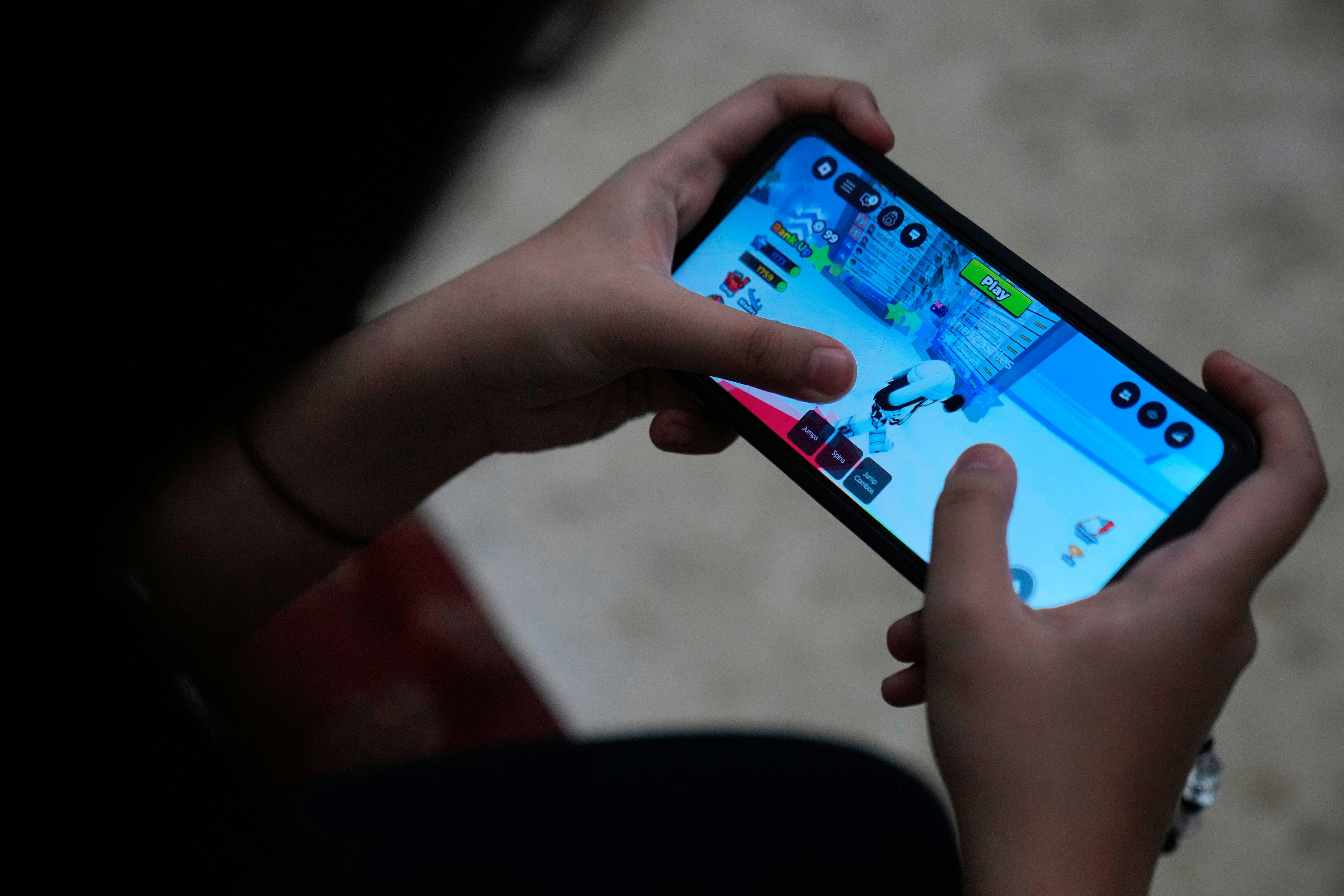 A girl plays Roblox on her mobile phone in Jakarta, Indonesia. Photo: AP