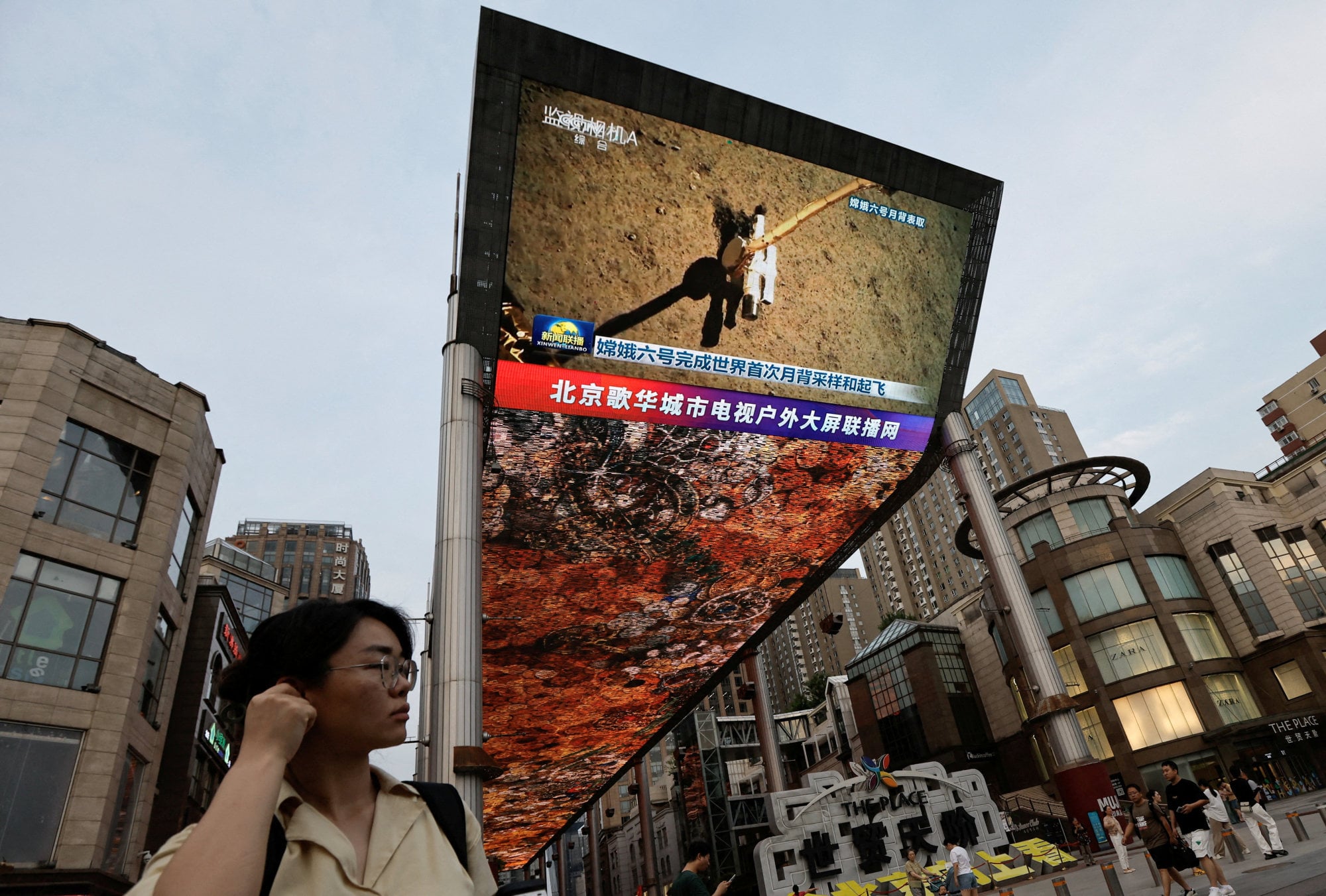 A large screen shows news footage of China’s Chang’e-6 lunar probe collecting a sample from the far side of the moon, in Beijing in June 2024. Photo: Reuters