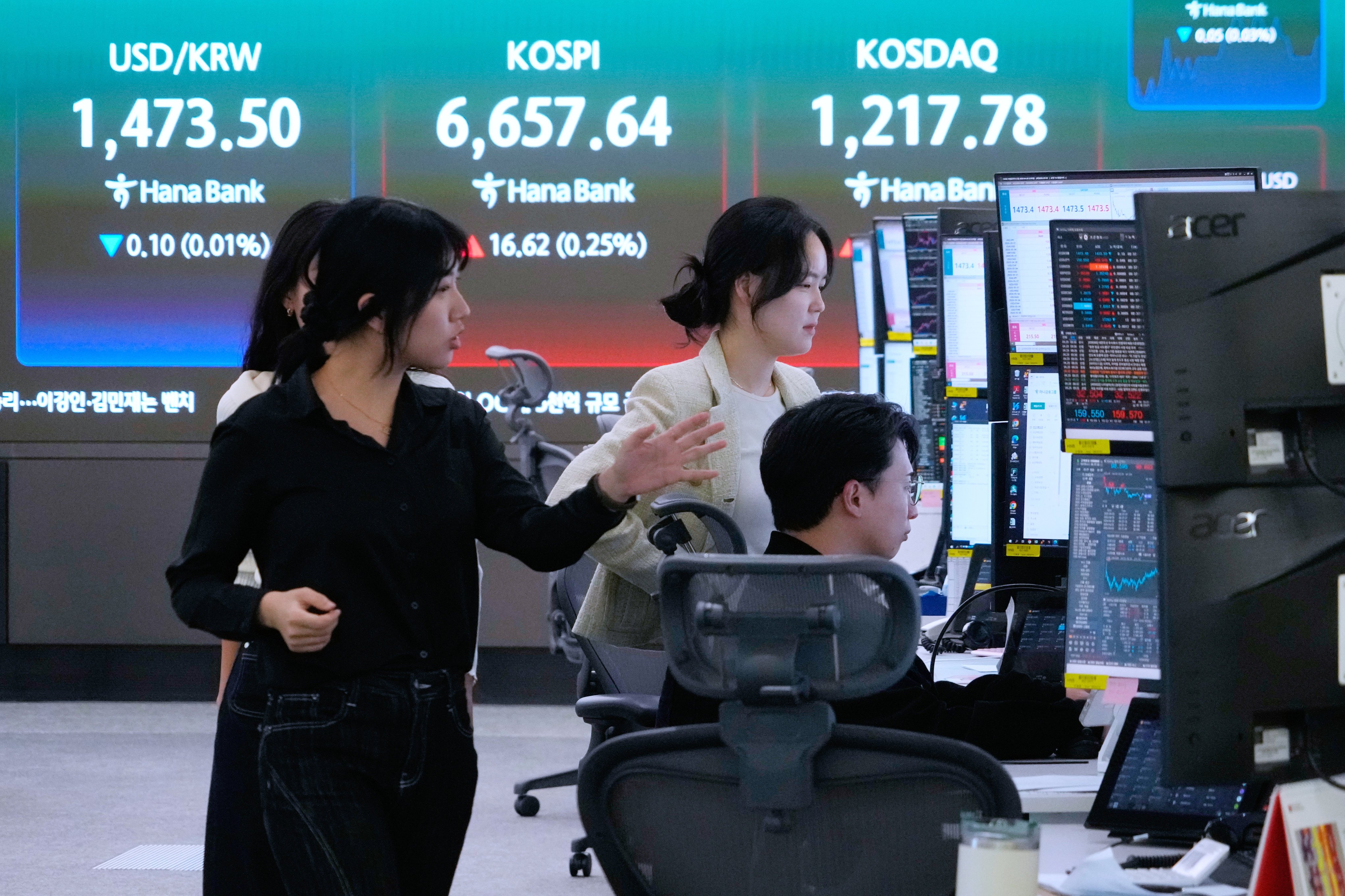Currency traders work near a screen showing the Korea Composite Stock Price Index and the dollar-won exchange rate at the Hana Bank headquarters in Seoul on April 29. Photo: AP