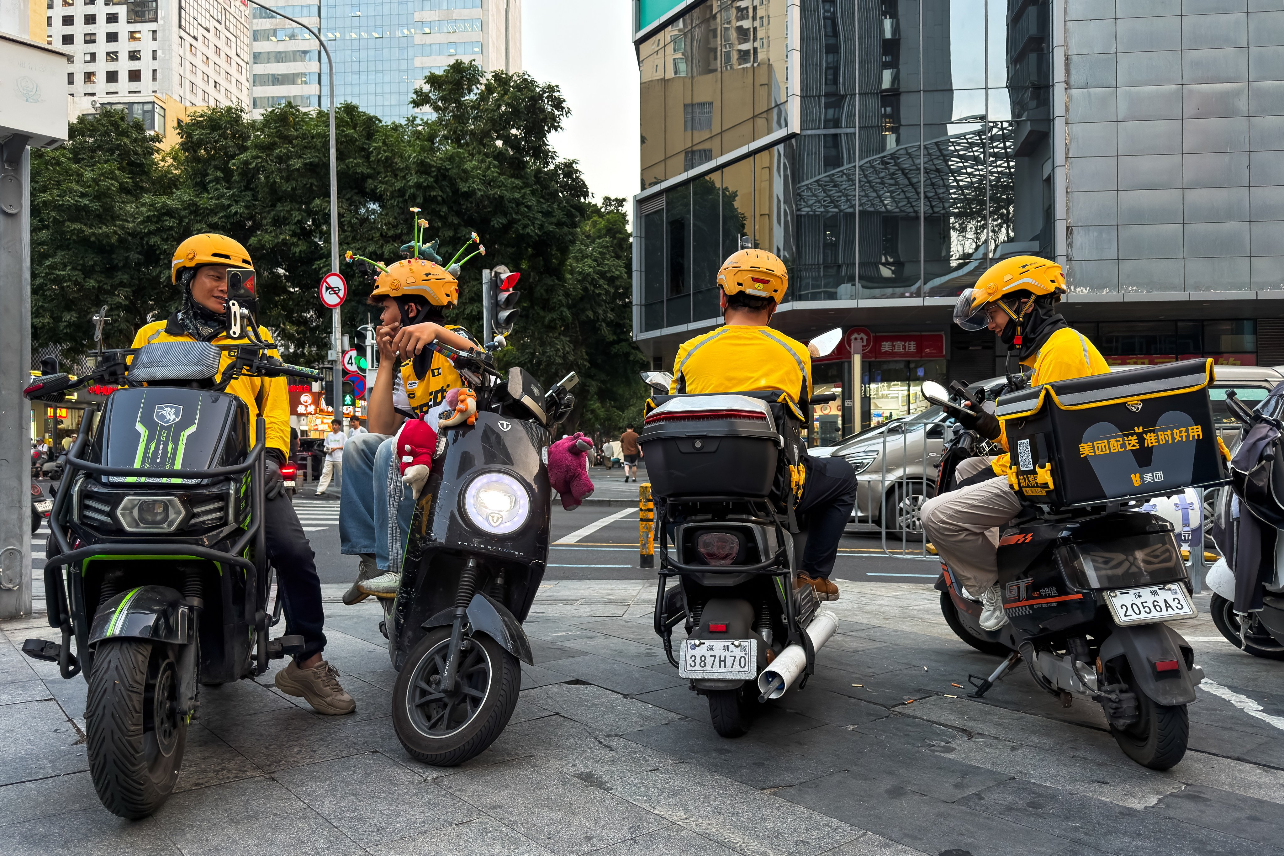 Delivery riders sit on scooters while waiting for orders at an intersection on March 24 in Shenzhen. Photo: Getty Images